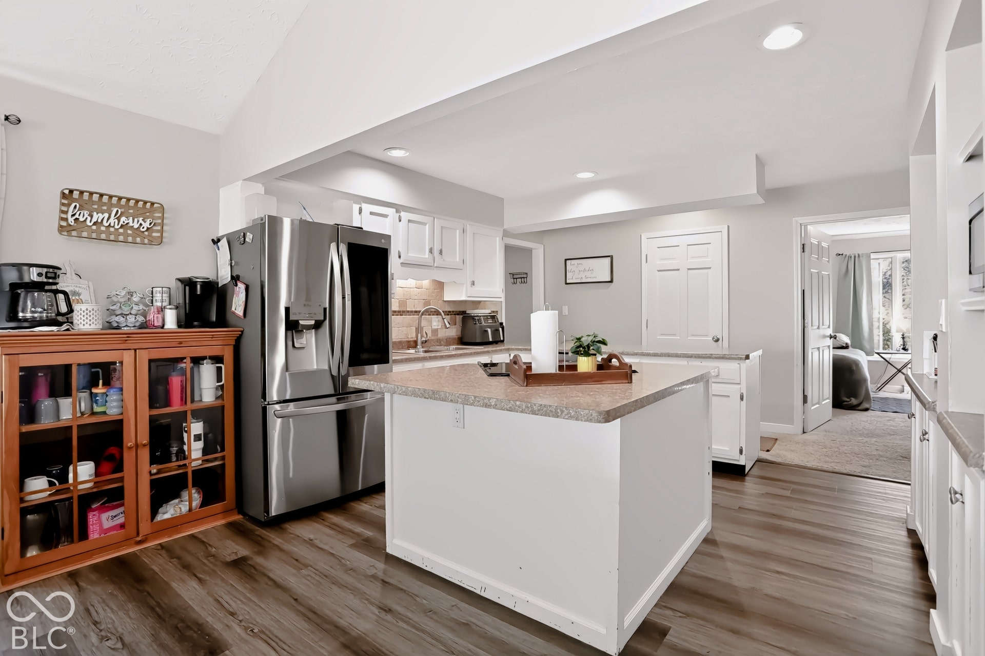 Kitchen featuring white cabinetry, light countertops, wood-finish flooring, recessed lighting, and a stainless steel refrigerator