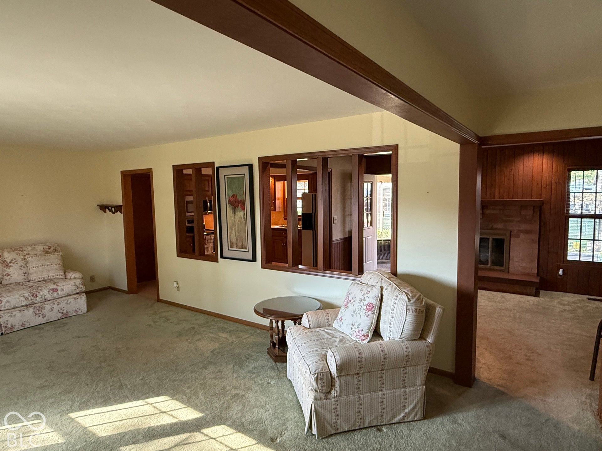 Central living area featuring carpet flooring, wood-framed interior windows, and a built-in shelf
