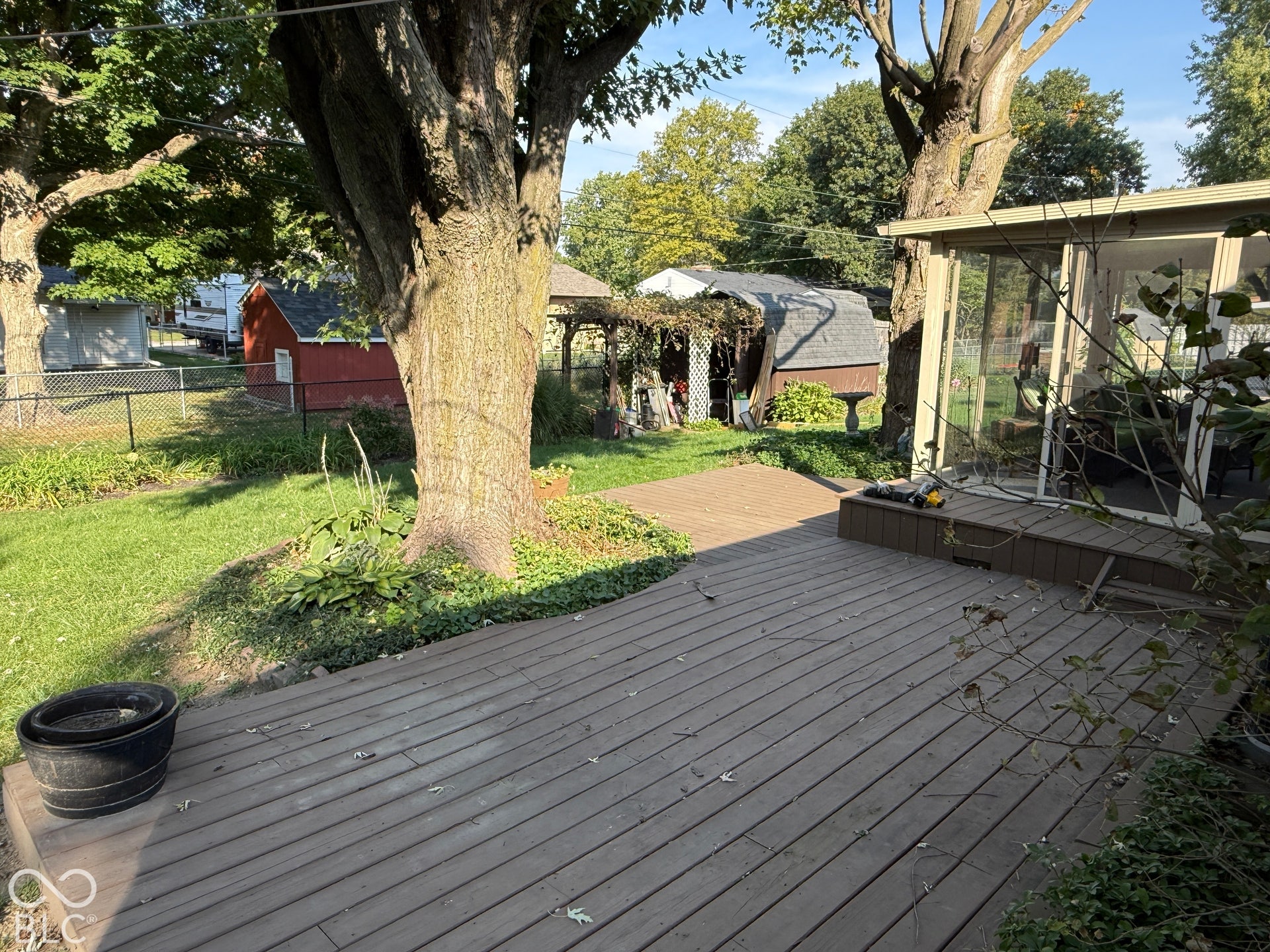 Expansive wooden deck with a built-in ramp, bordered by mature trees and a manicured lawn