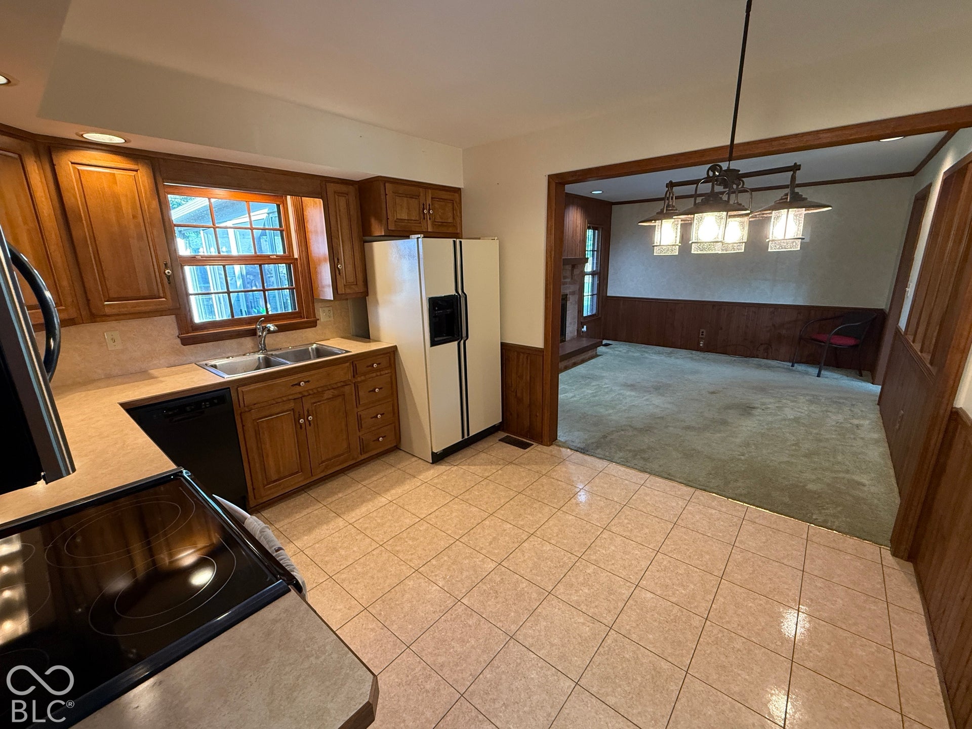 Kitchen featuring wood cabinetry, tiled flooring, a double basin stainless steel sink, and a built-in dishwasher