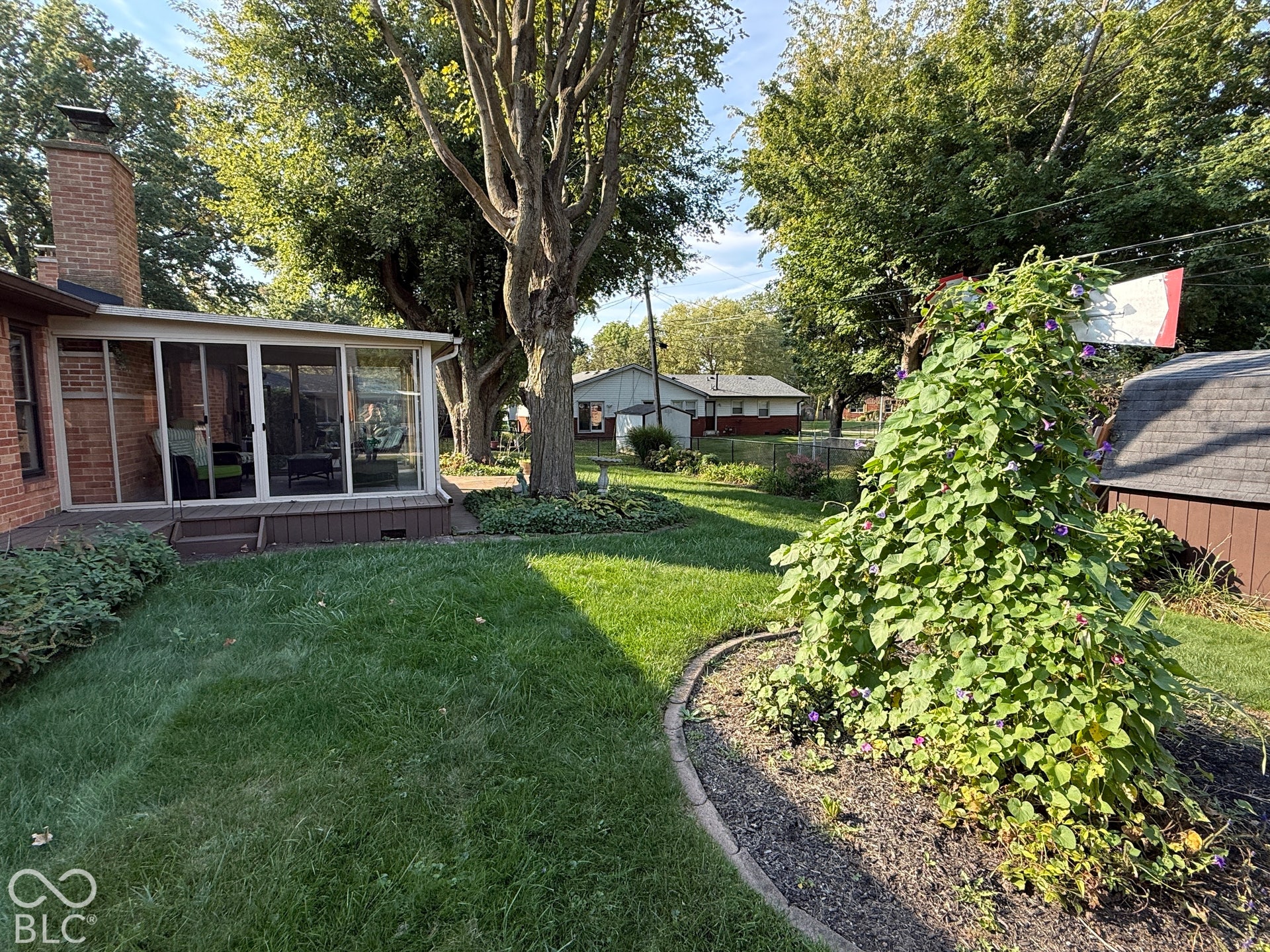 Expansive lawn with mature trees and a brick chimney