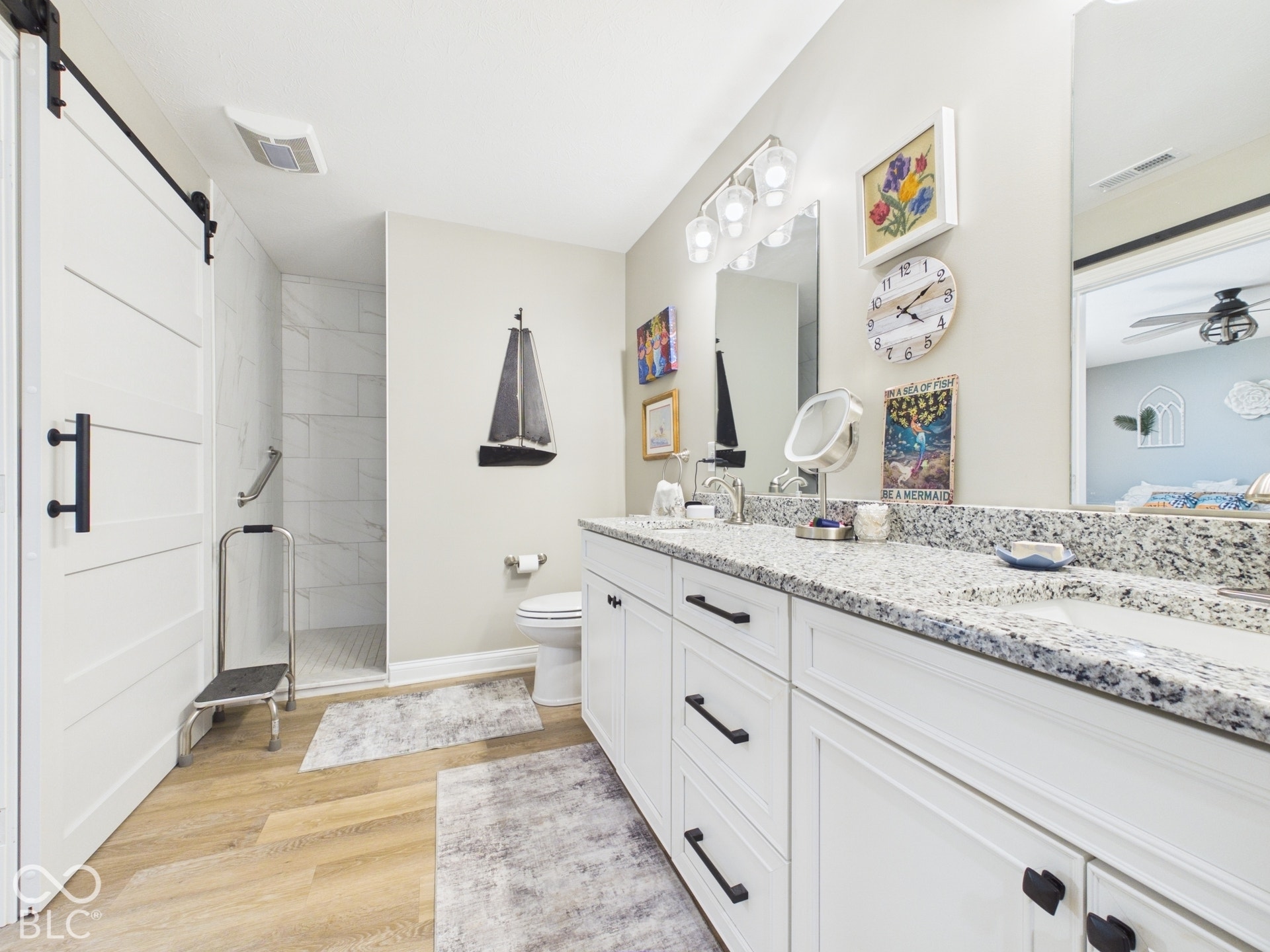Double vanity with granite countertops, white cabinetry, and matte black hardware
