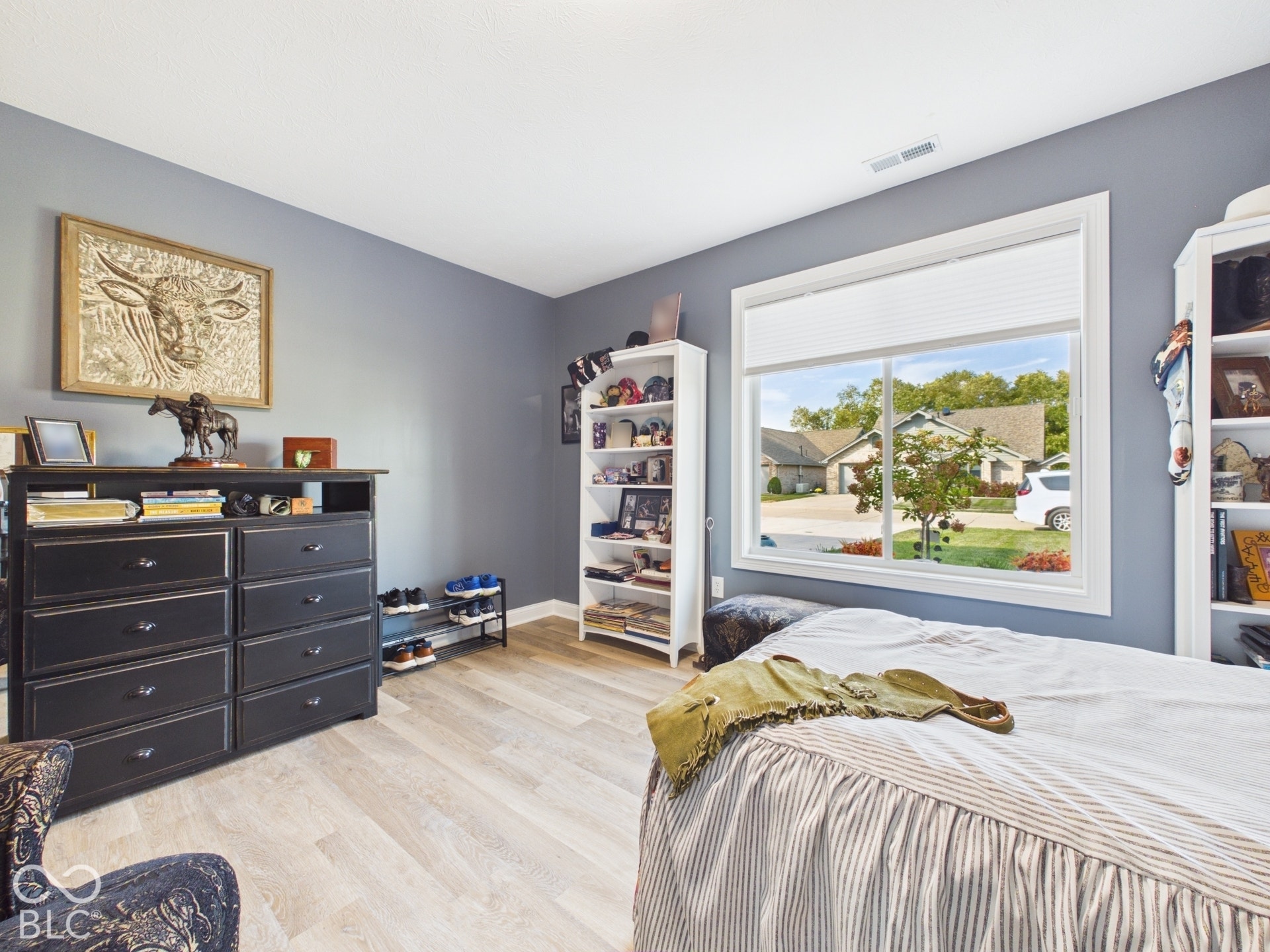 Light-toned wood-finish flooring, white window trim, and a window with a pleated shade