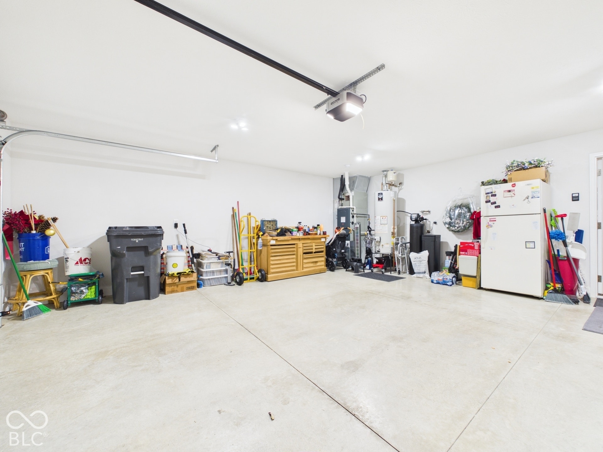 Brightly lit garage with a concrete floor, white walls, and an overhead garage door opener