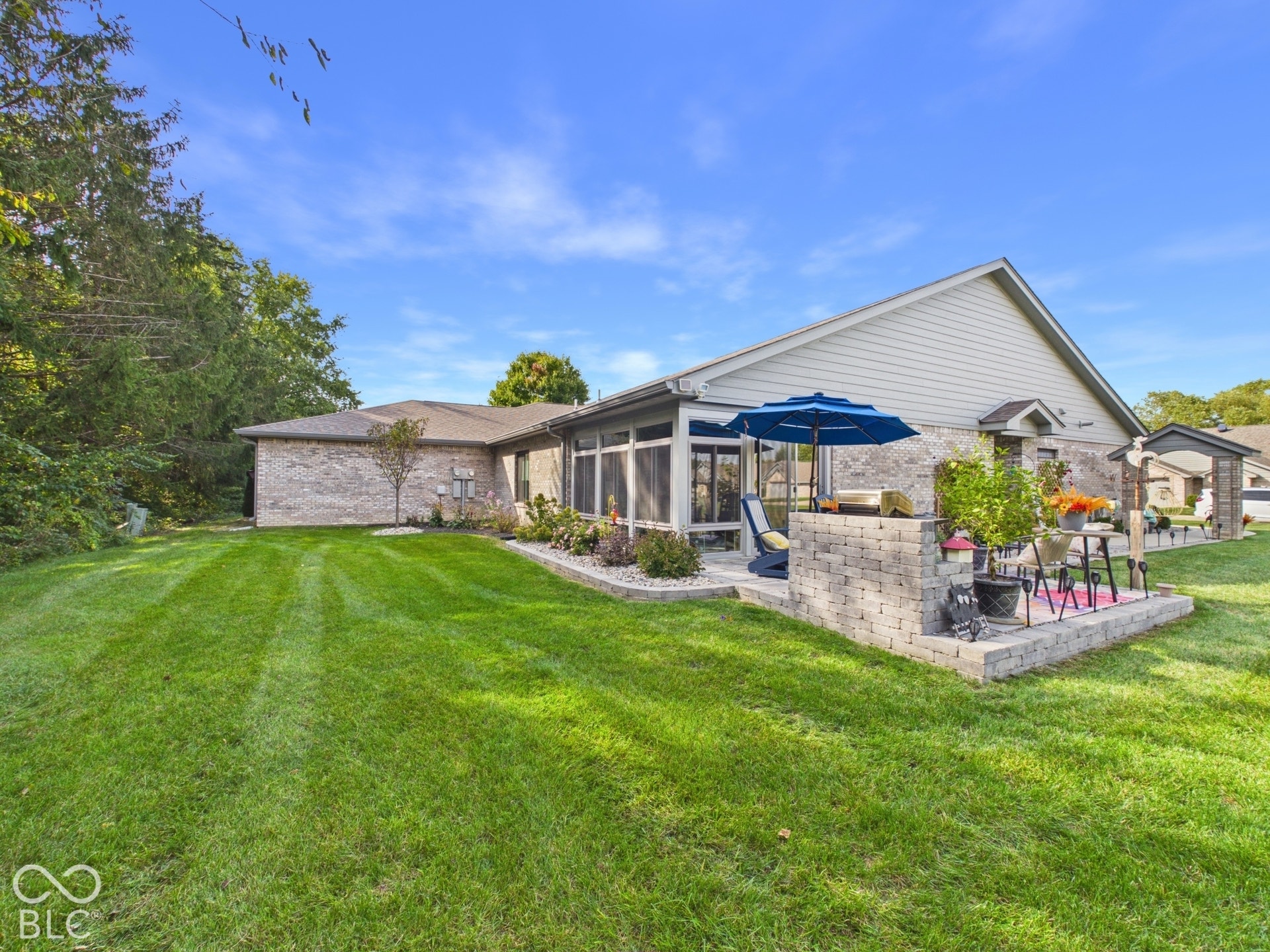 Expansive lawn with a paver patio, screened-in porch, and brick exterior