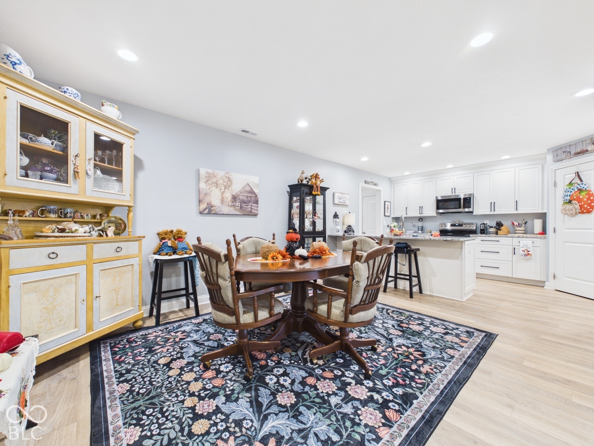 Recessed lighting, wood-finish flooring, white cabinetry, integrated stainless steel appliances, and a built-in kitchen island