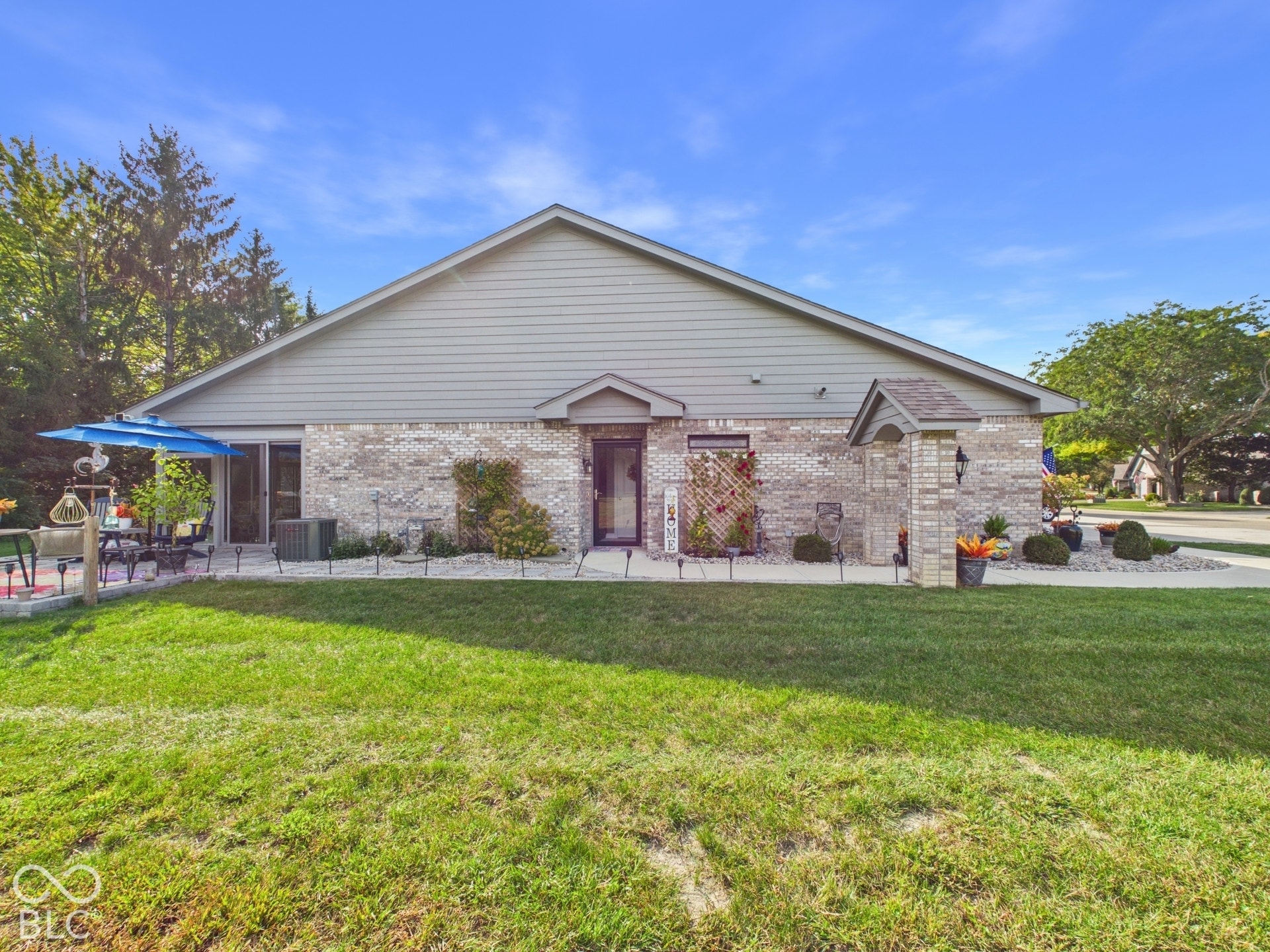 Brick exterior with siding gable, patio area, sliding glass door, paved walkway, and landscaping