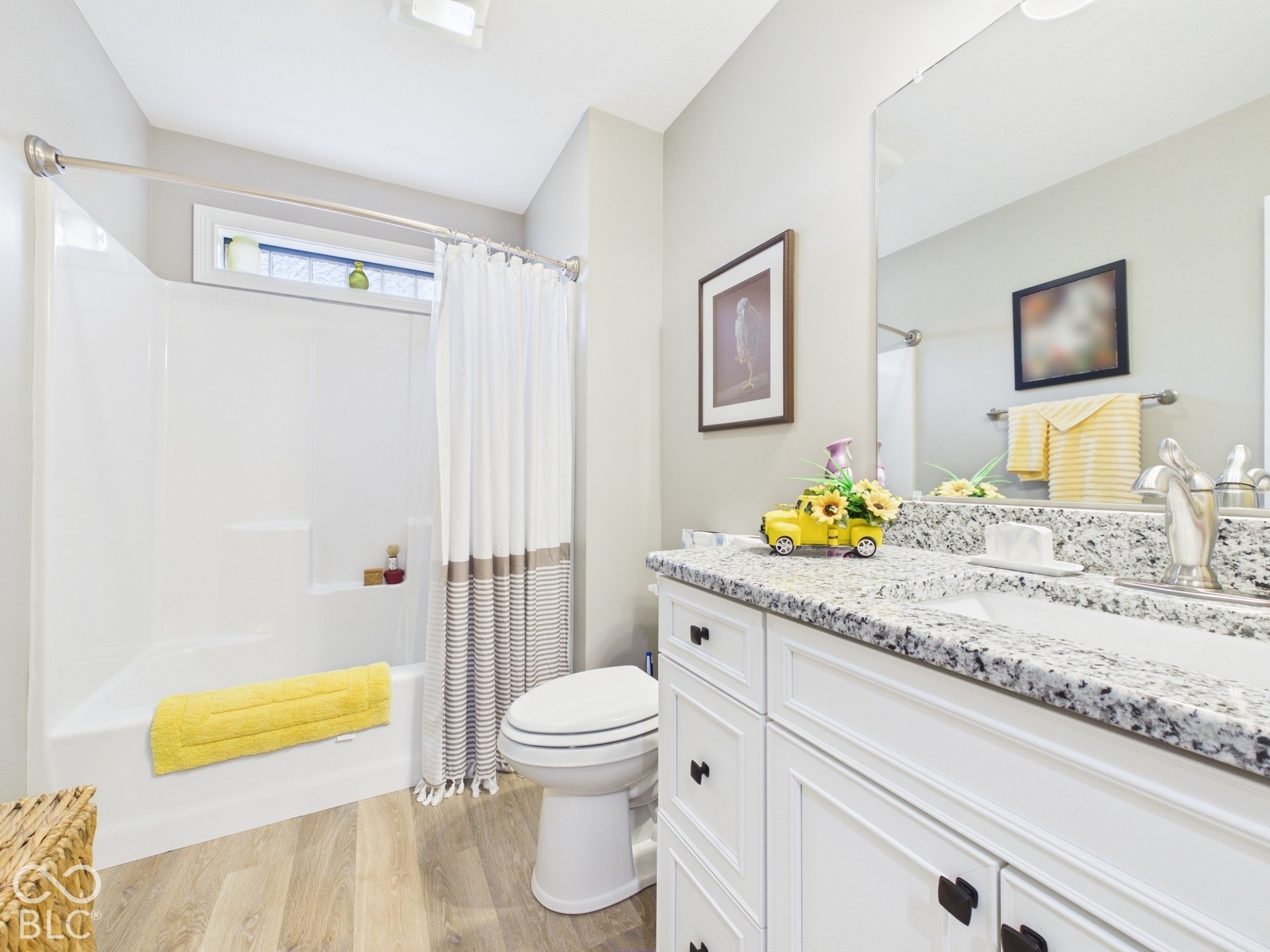 White vanity with a speckled countertop, integrated sink, and brushed nickel faucet