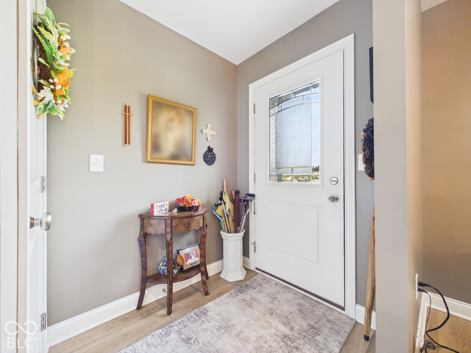 Entryway featuring a paneled door with decorative glass inserts, light wood-finish flooring, and neutral wall tones