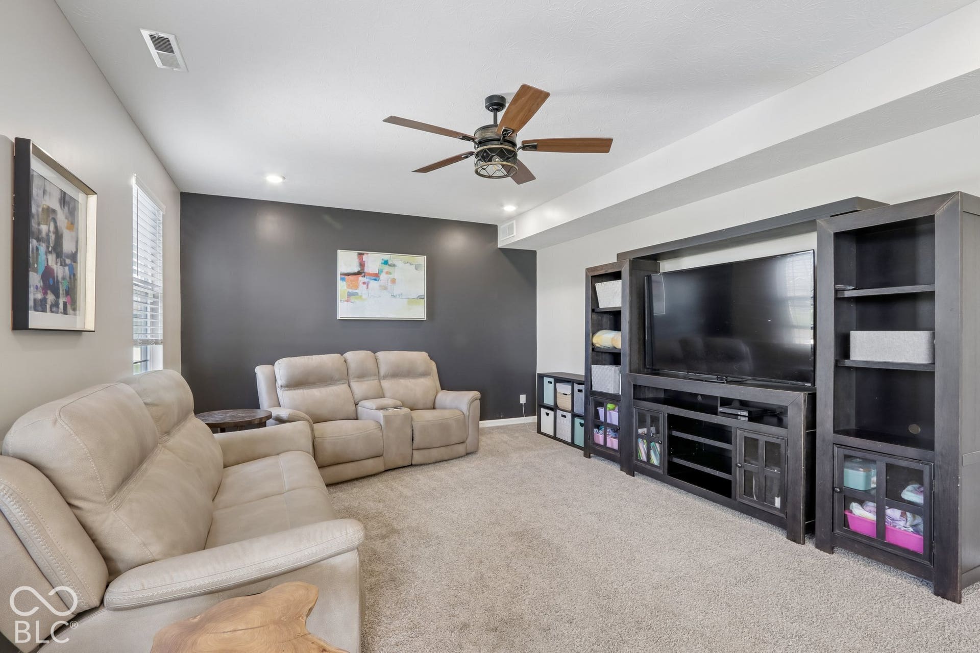 Recessed lighting, ceiling fan with wood-finish blades, and a dark accent wall