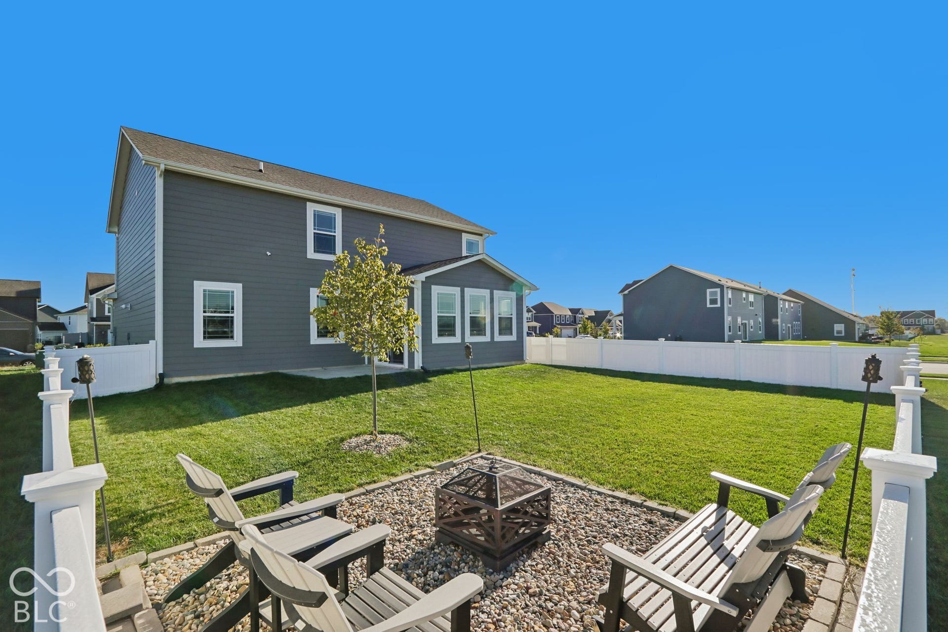 Expansive fenced backyard with a gravel fire pit area, featuring a well-maintained lawn