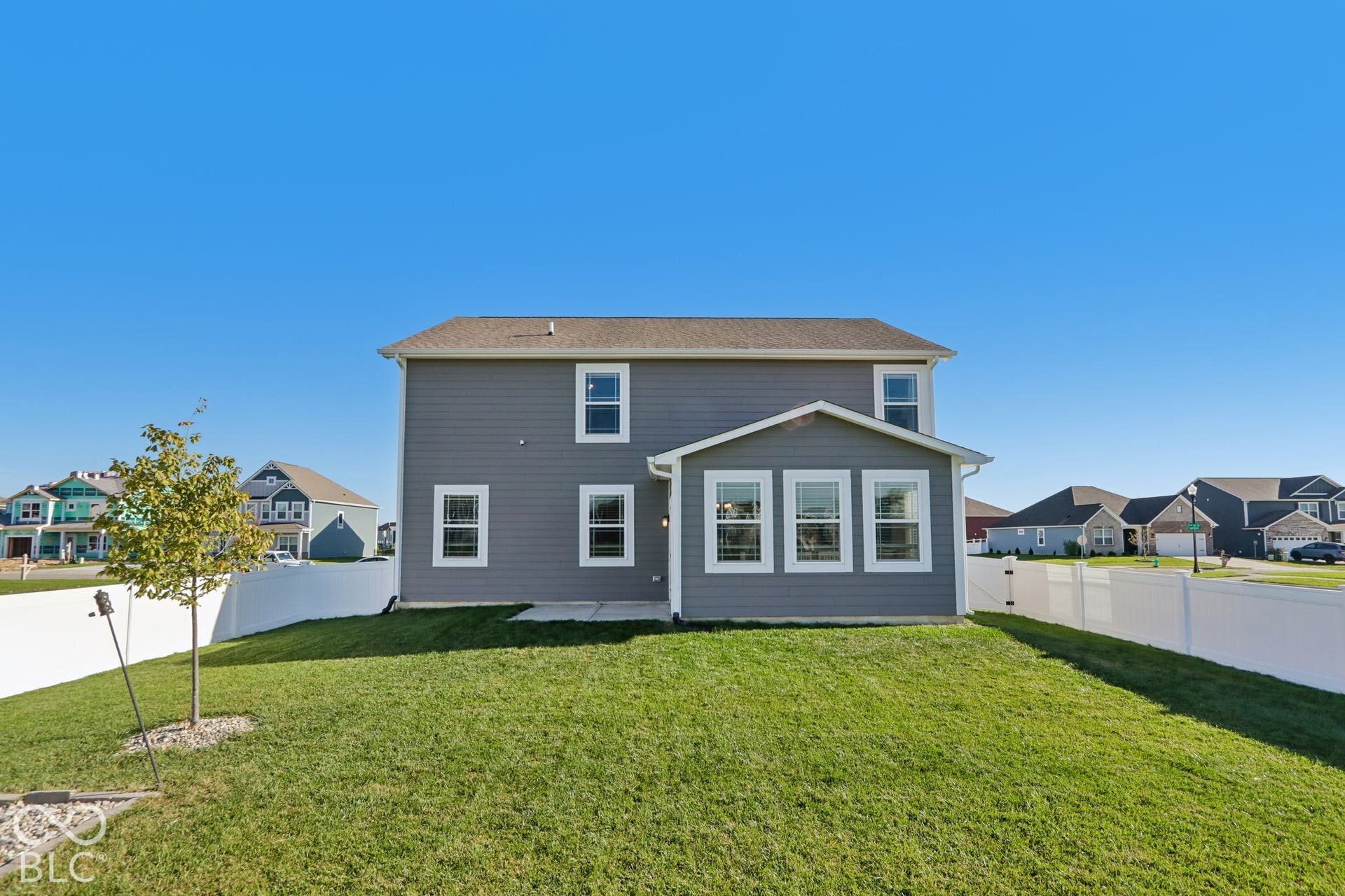 Two-story exterior with gray siding, a gabled roof, and a rear patio