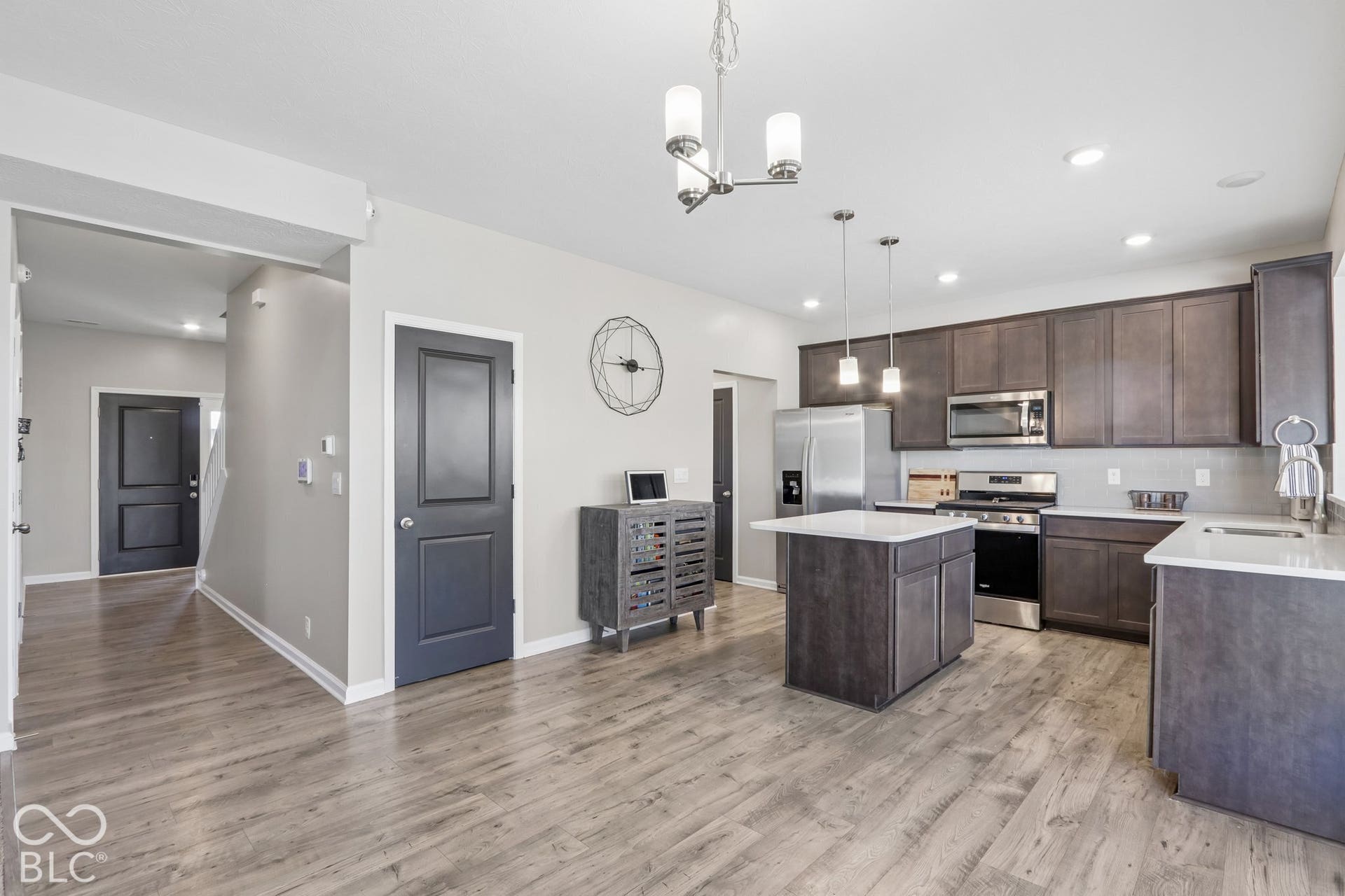 Kitchen featuring a central island, white quartz countertops, dark cabinetry, light gray subway tile backsplash, and stainless steel appliances