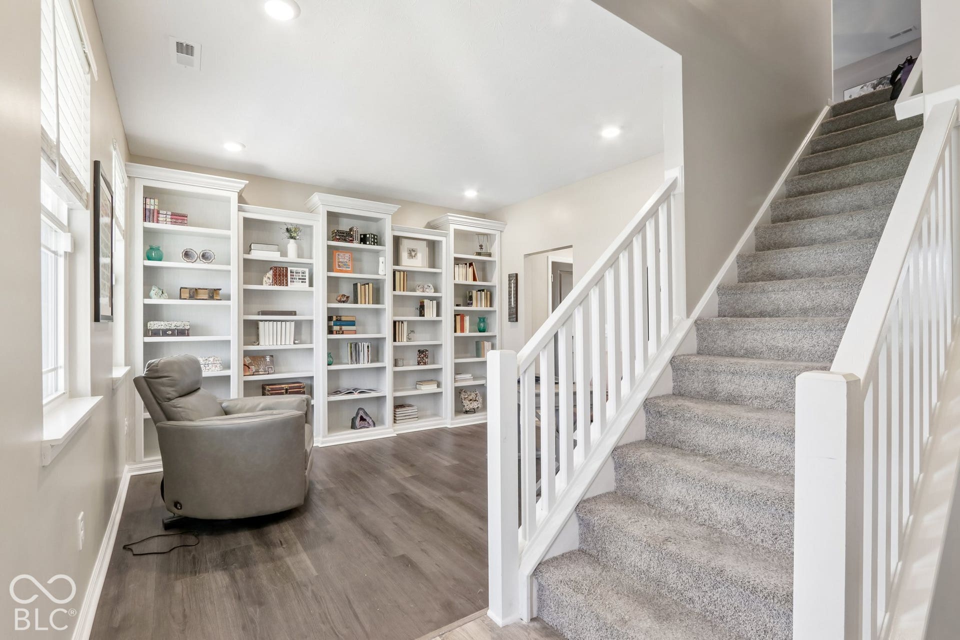 Built-in shelving, recessed lighting, wood-finish flooring, and a carpeted staircase with white railings