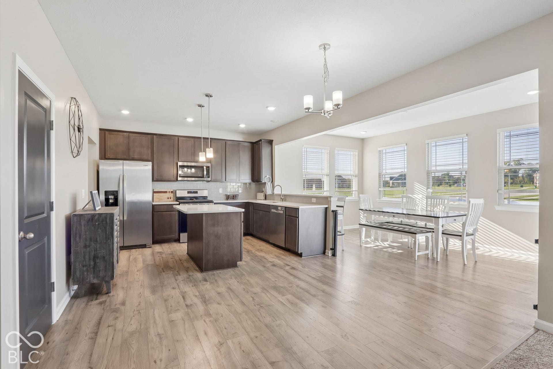 Kitchen featuring a central island, white quartz countertops, dark cabinetry, light gray subway tile backsplash, and stainless steel appliances