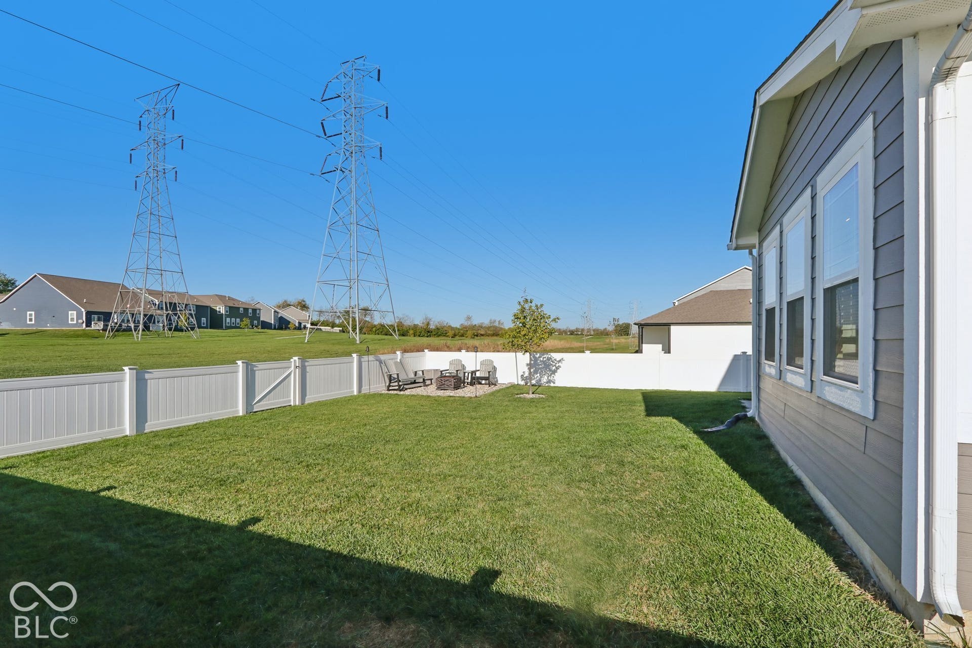 Expansive grass lawn with a white privacy fence