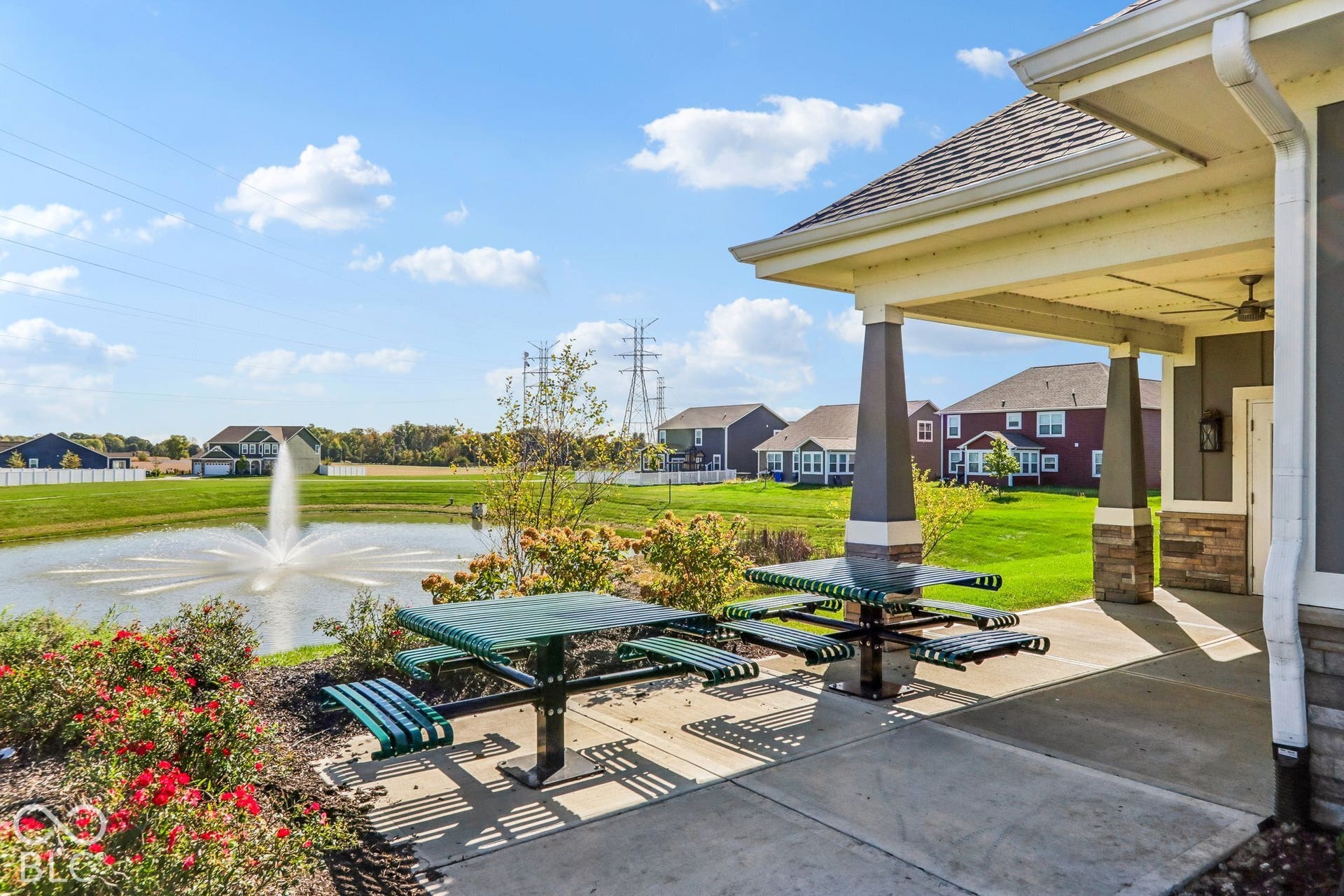Edgewood Farms Community Clubhouse with covered patio with, integrated pergola and ceiling fans overlooking manicured lawn and water feature