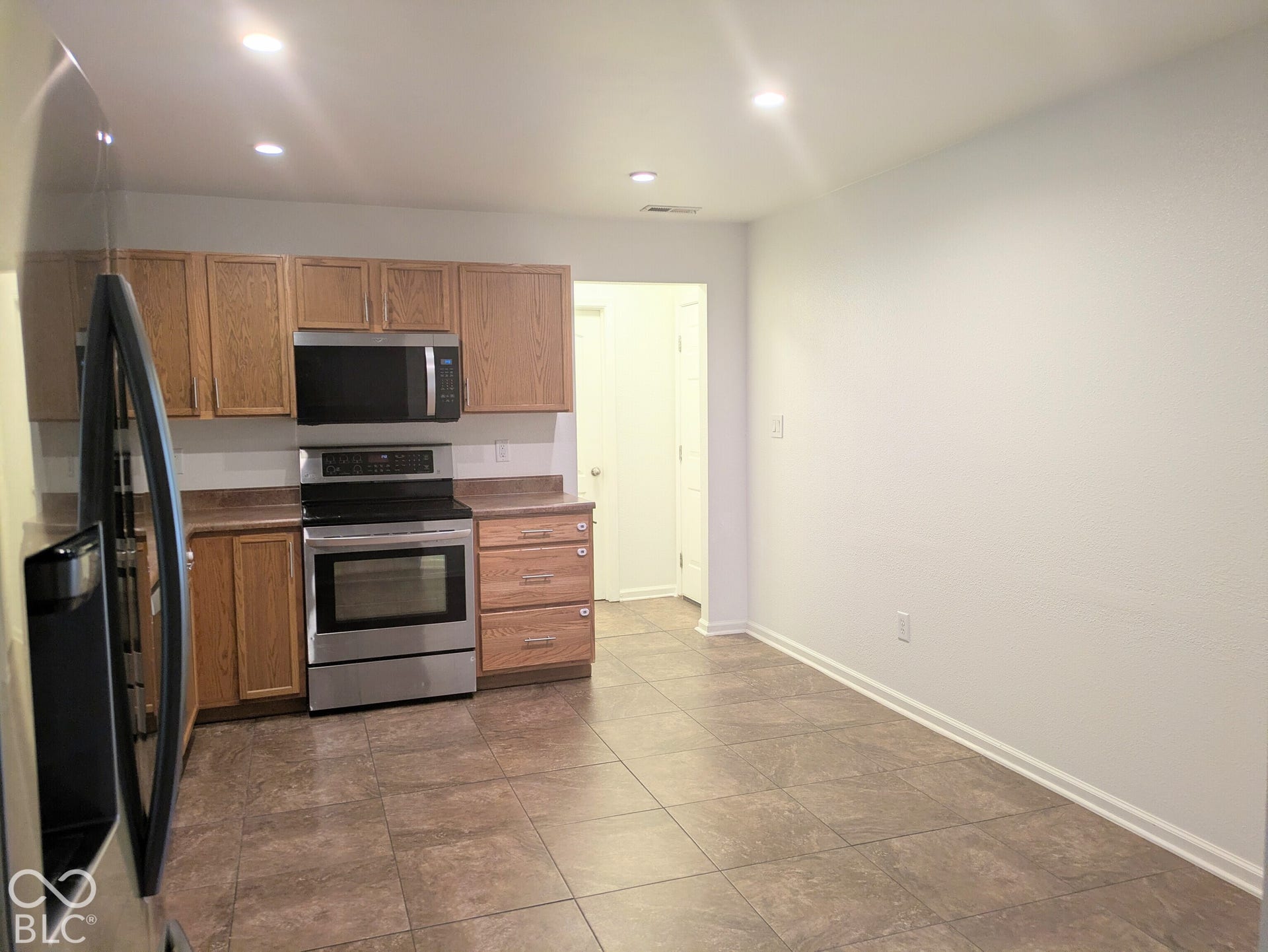 Kitchen featuring wood-finish cabinetry, stainless steel oven and microwave, recessed lighting, and tile flooring