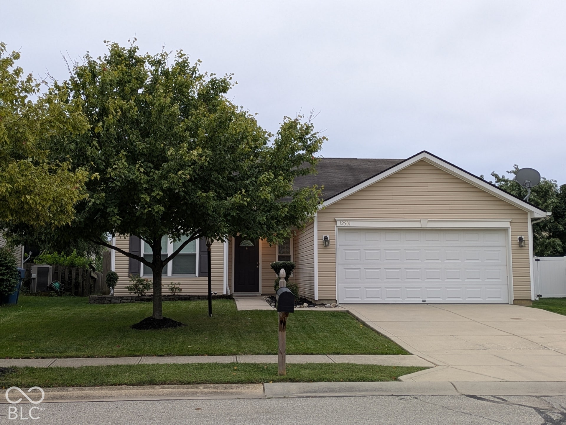 Single-story residence featuring light-colored siding, an attached two-car garage, a concrete driveway, and a front entry