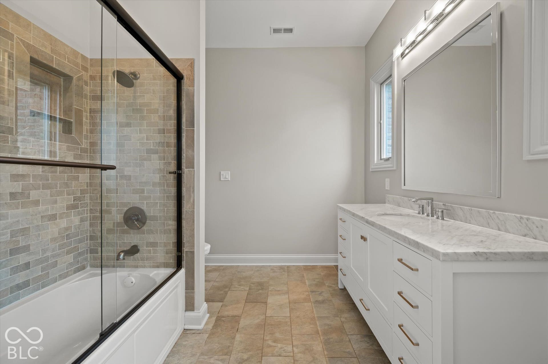 White vanity with a light-toned countertop, modern light fixture, and large mirror