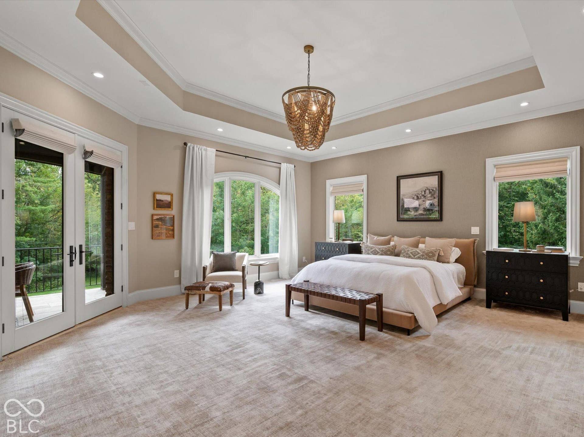 Tray ceiling with recessed lighting, arched window, French doors with exterior balcony, and textured wall-to-wall carpeting