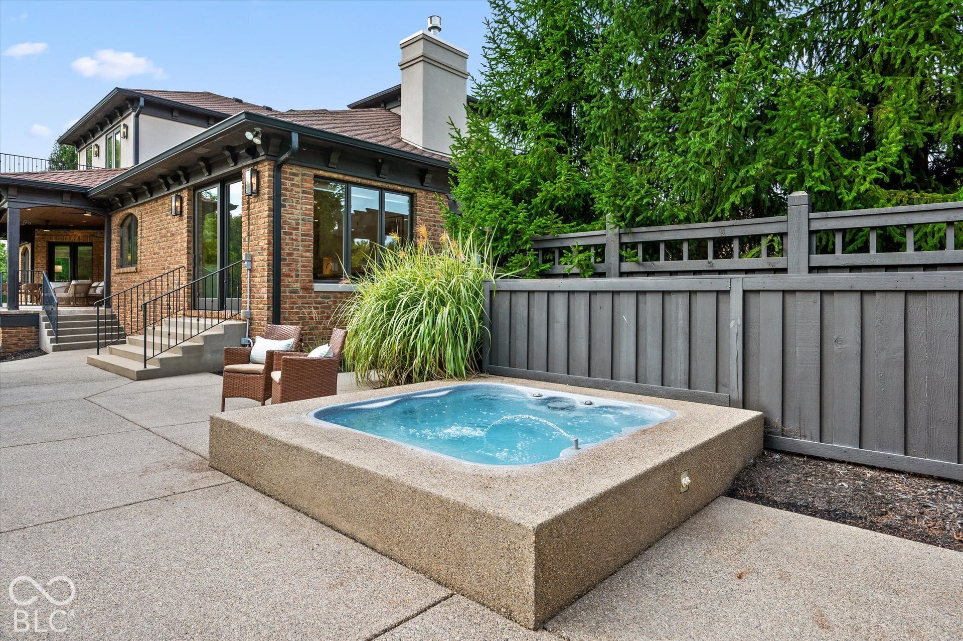 Integrated spa with surrounding hardscaping, brick exterior, and a privacy fence