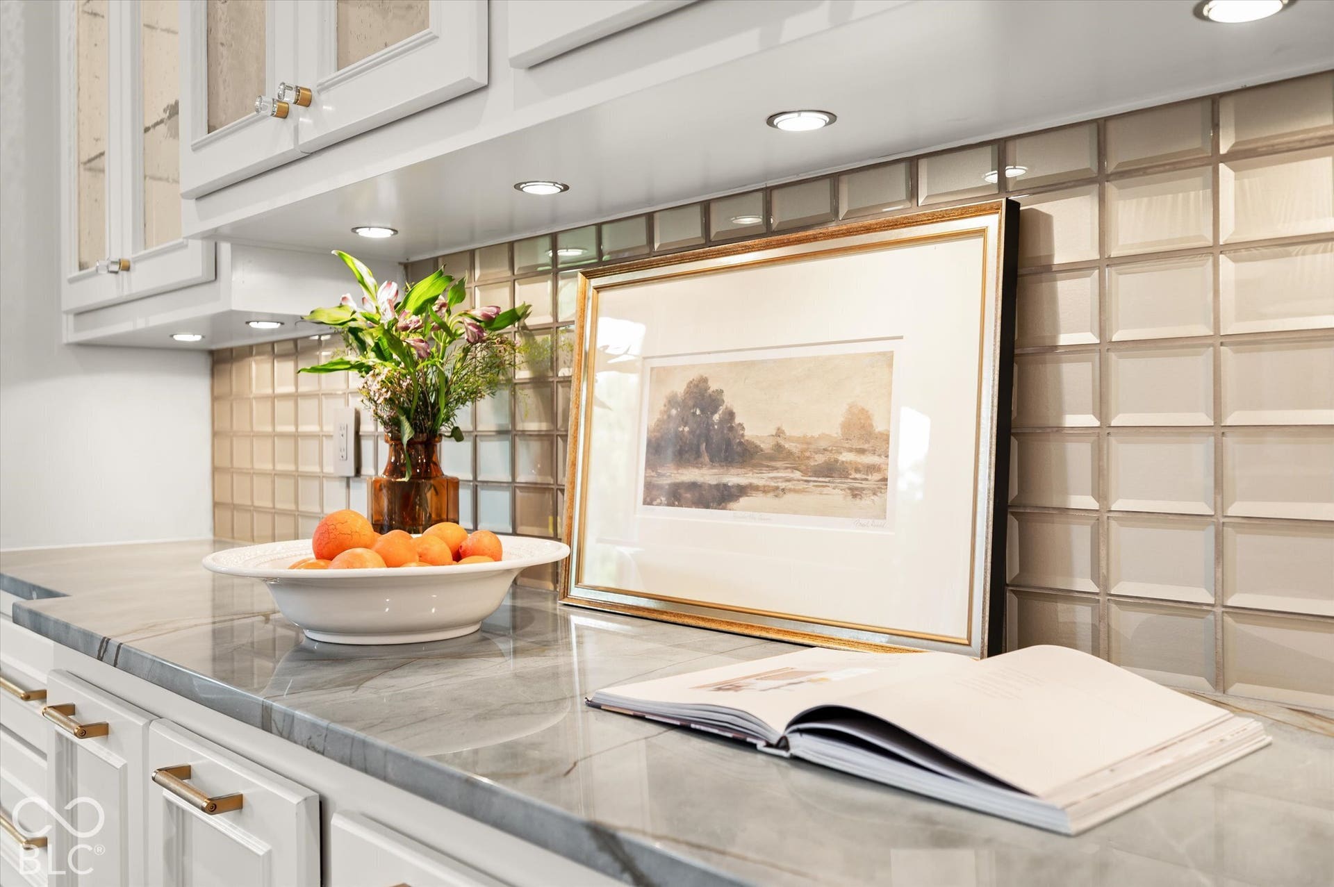 White cabinetry with gold-tone hardware, recessed lighting, polished stone countertop, and a tiled backsplash
