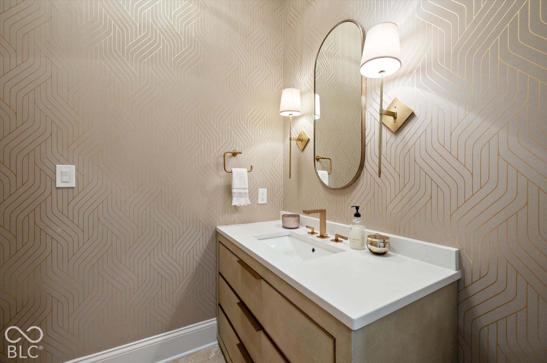 Patterned wallpaper accentuates the space, complemented by a vanity with a white countertop and gold-finish hardware