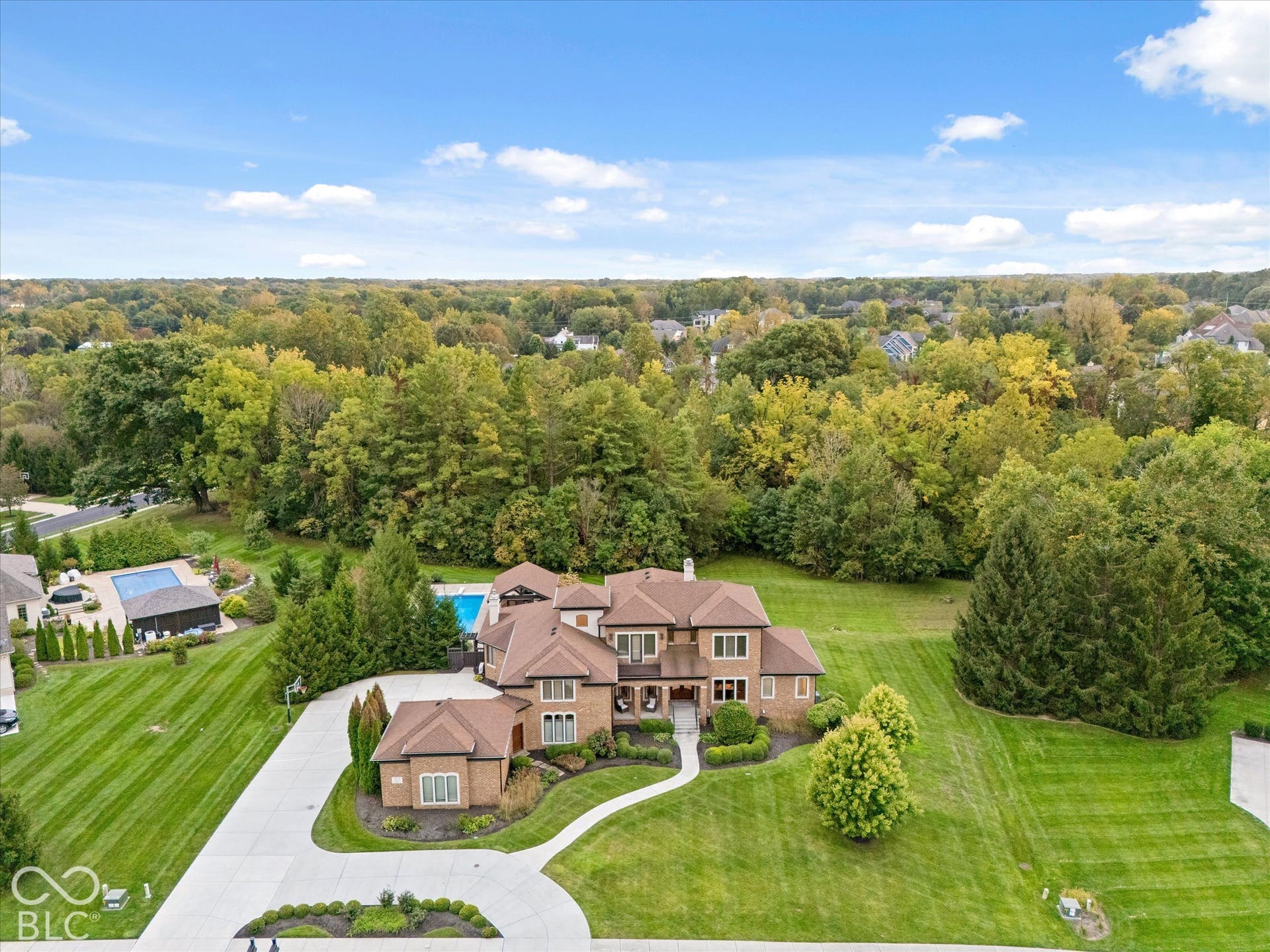 Stately brick residence featuring a multi-level design, an expansive concrete driveway, and professional landscaping