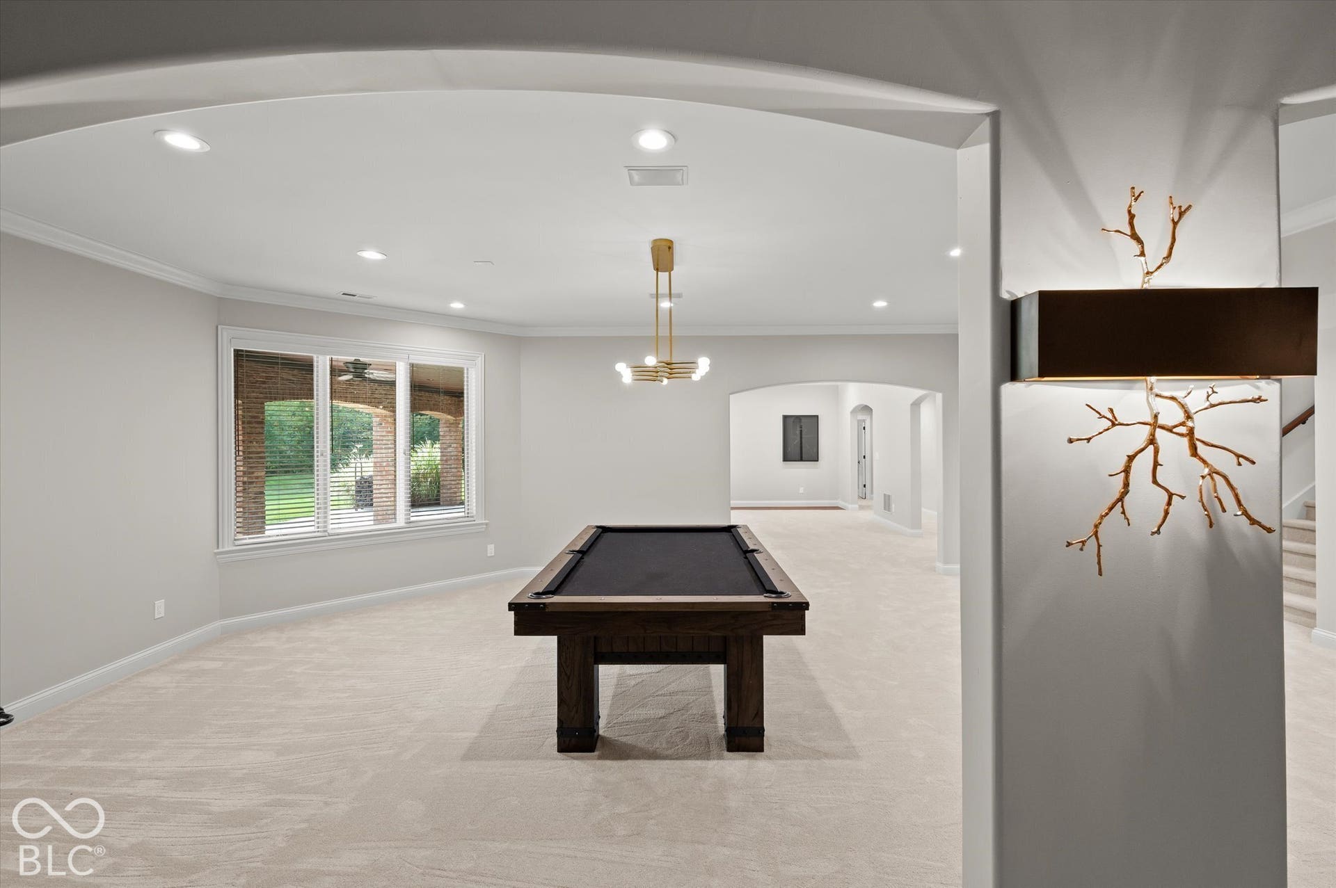 Recessed lighting, arched doorway, large window, crown molding, and wall sconce