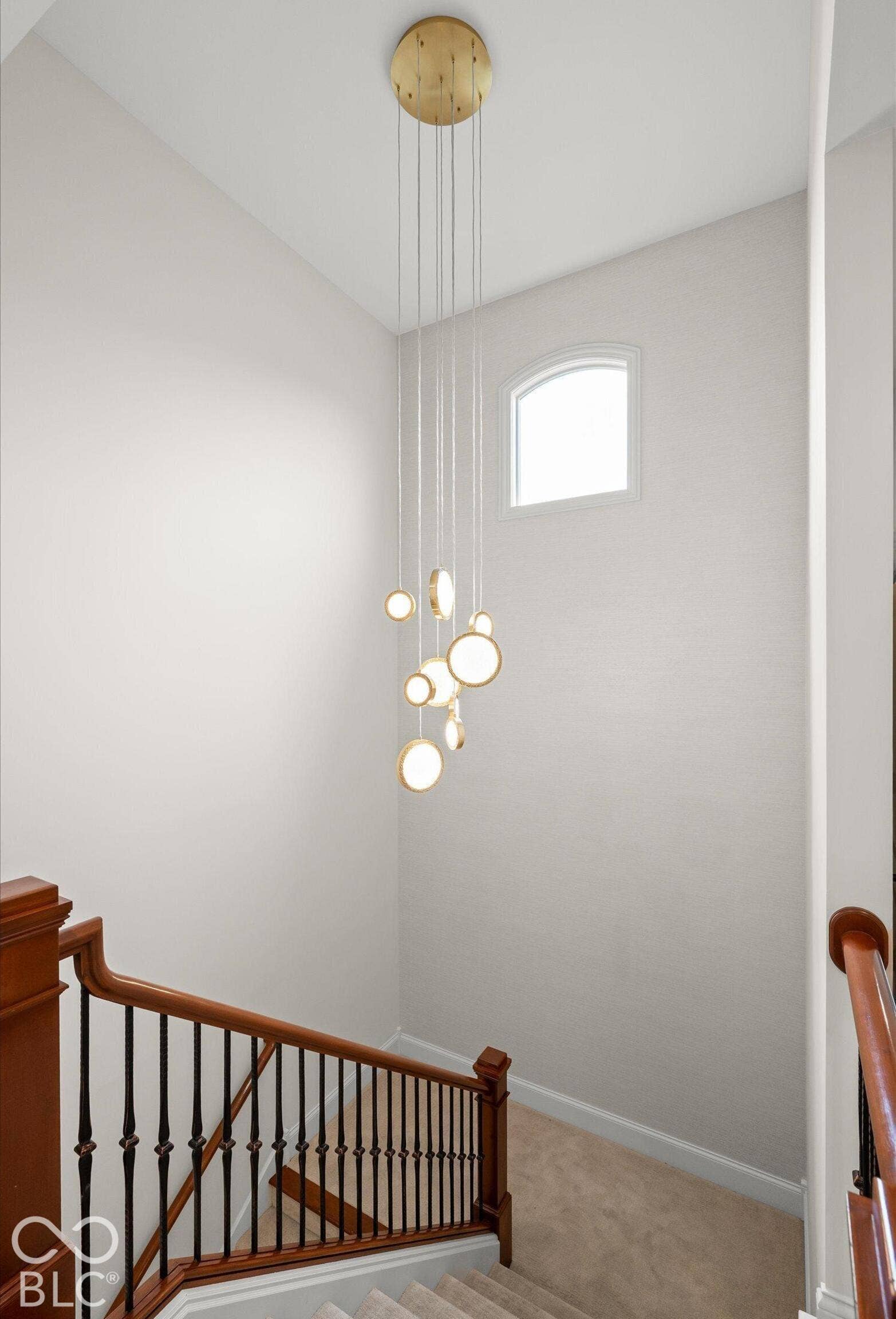 Staircase featuring wood handrails, wrought iron balusters, and a carpeted tread