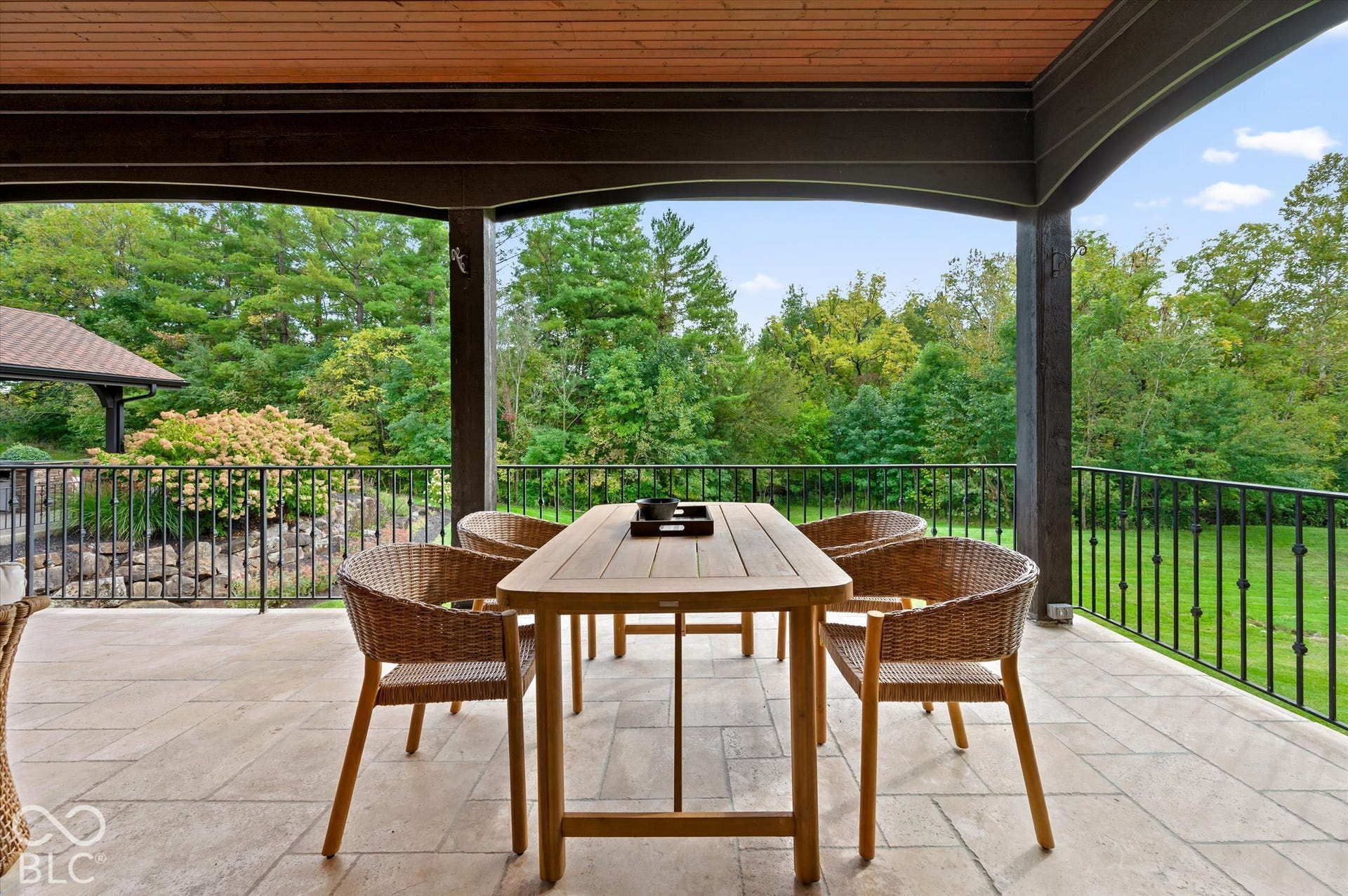 Expansive covered patio featuring a tiled surface, dark wood-finish ceiling, and wrought iron railings