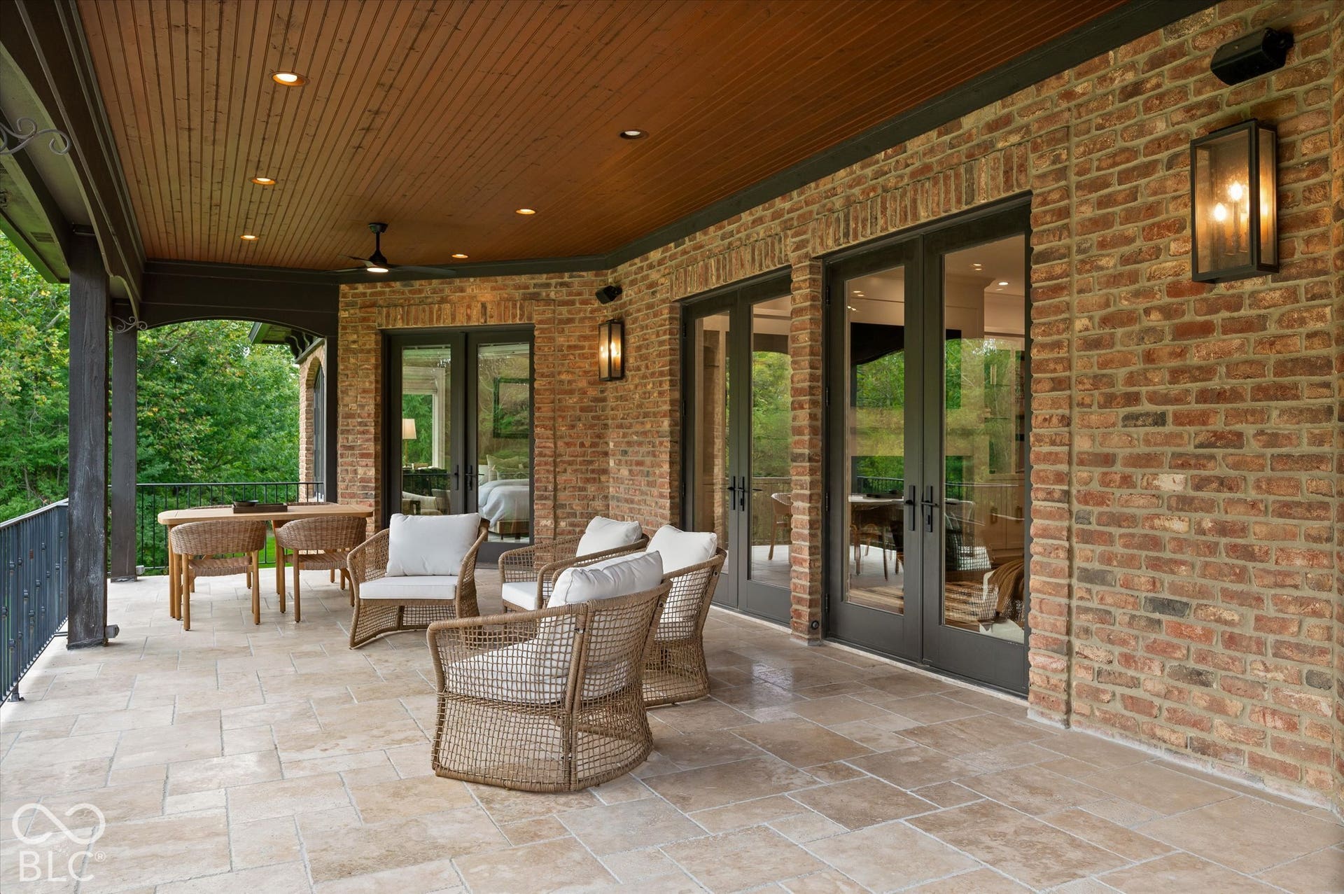 Spacious outdoor patio featuring durable tile flooring, a wood-paneled ceiling, and brick exterior walls