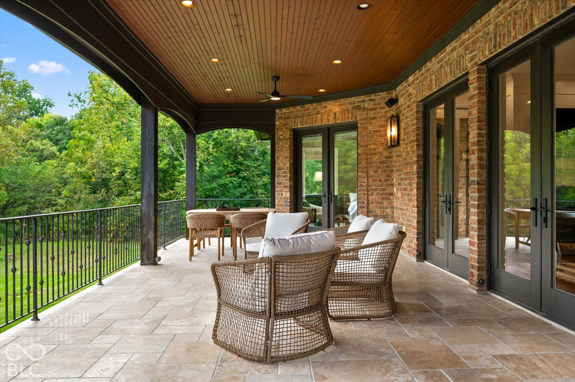 Expansive covered patio with brick exterior, stone tile flooring, and wood-paneled ceiling