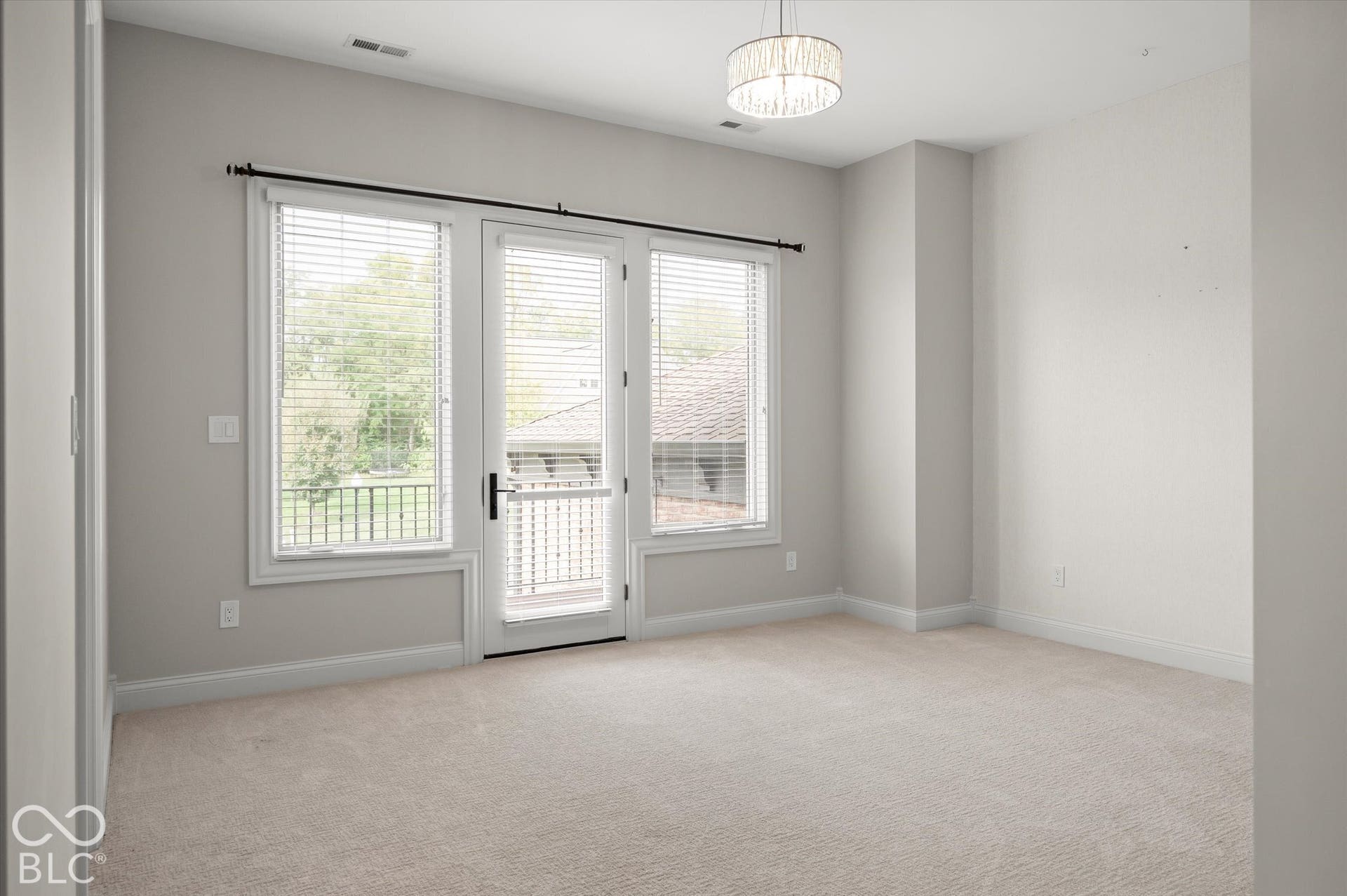 Light-colored carpeting with white trim, a decorative ceiling fixture, and double glass doors