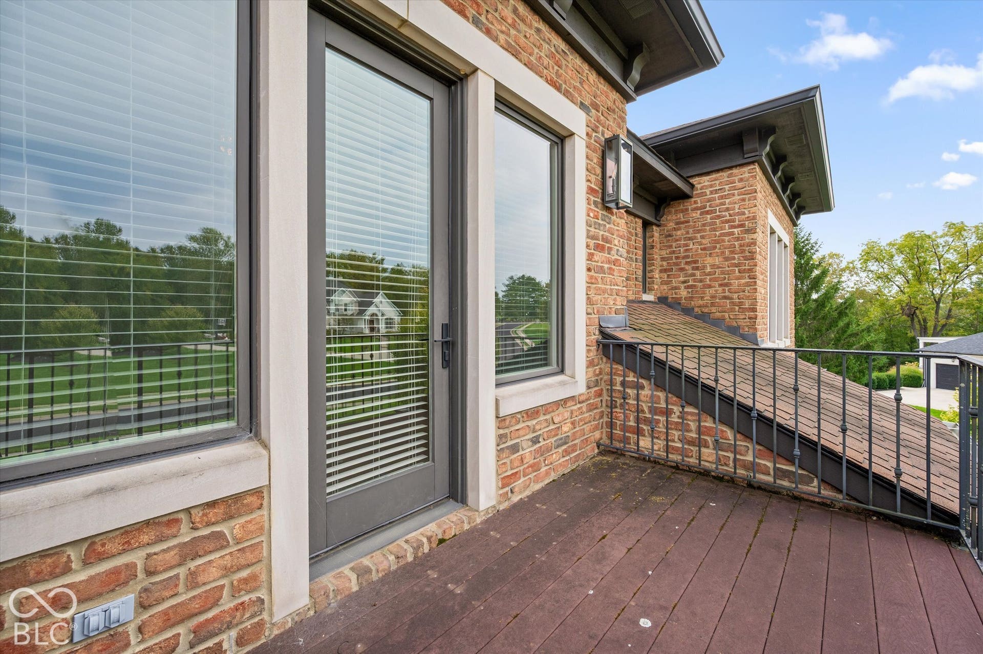 Deck with wood-finish flooring, brick exterior, and dark-framed glass door
