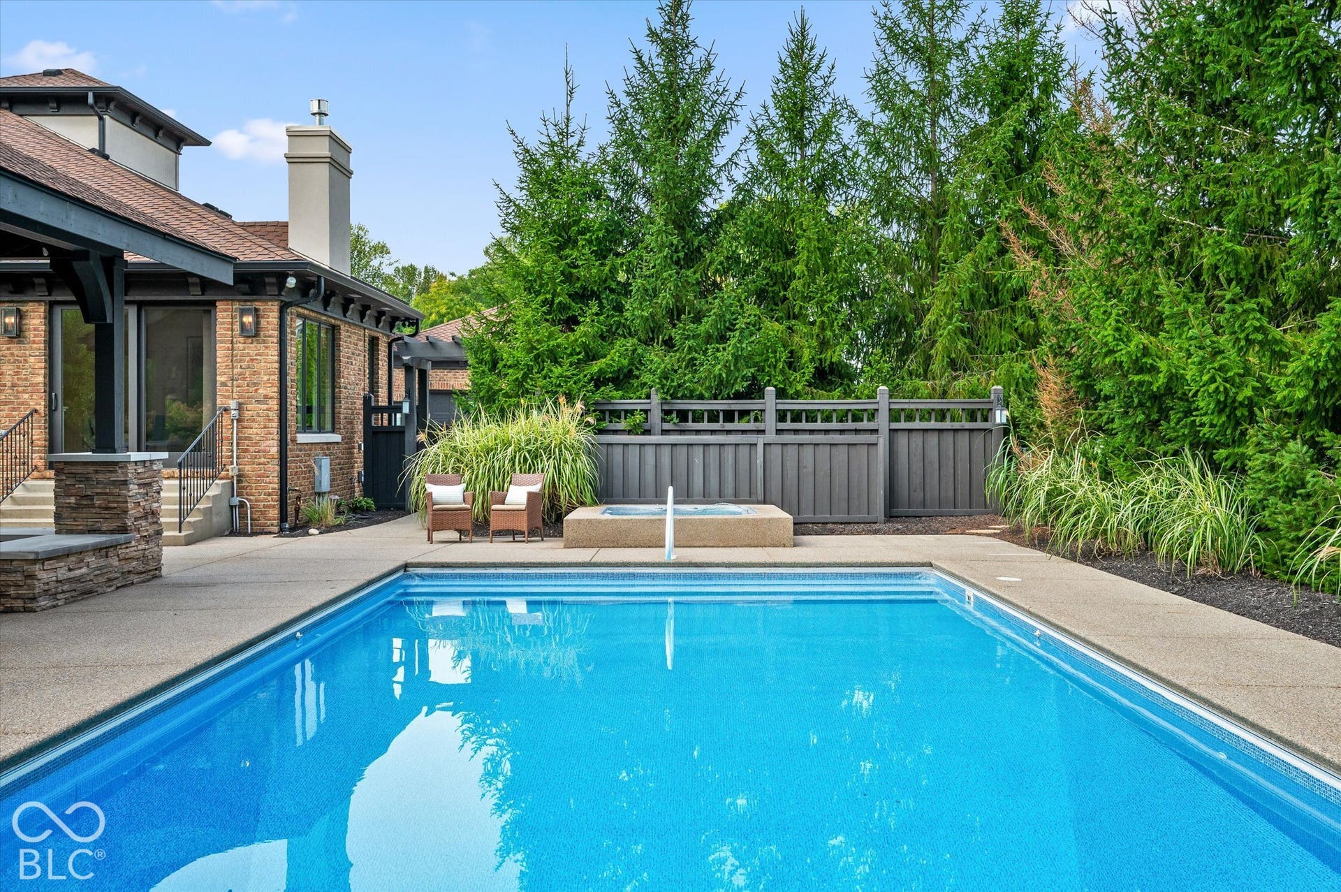 Expansive outdoor living area featuring a rectangular swimming pool, integrated spa, and concrete pool deck