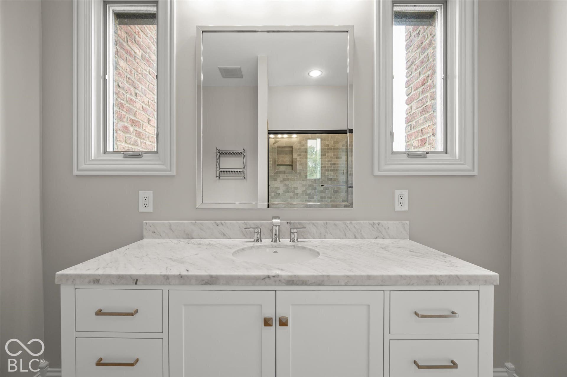 Vanity with white shaker cabinetry, gold-tone hardware, and a single undermount sink