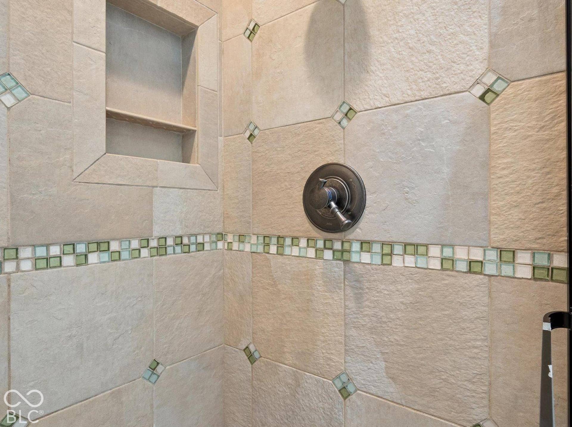 Tiled shower with a built-in niche, mosaic accent border, and oil-rubbed bronze fixtures