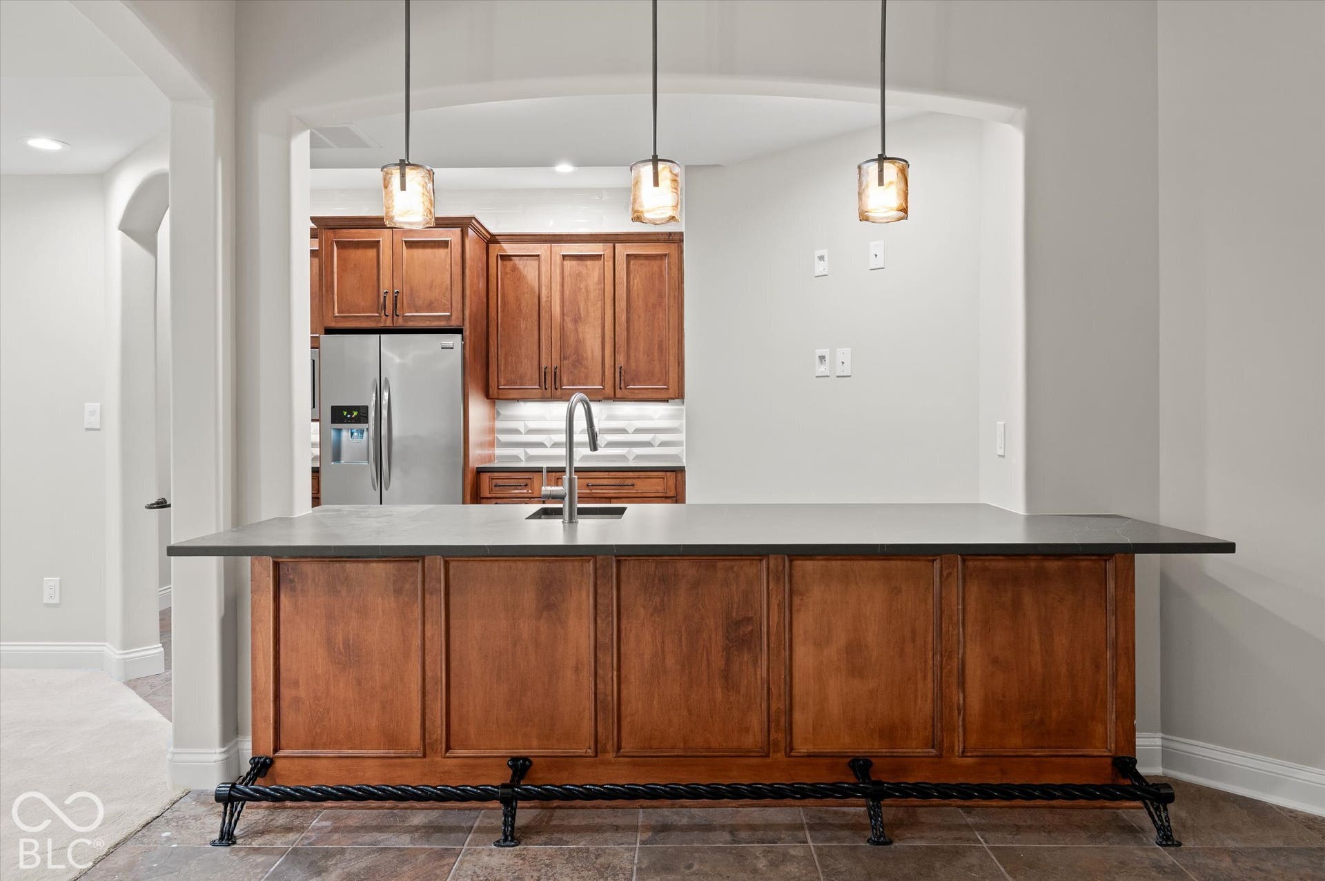 Built-in bar with wood cabinetry, dark countertop, and decorative foot rail