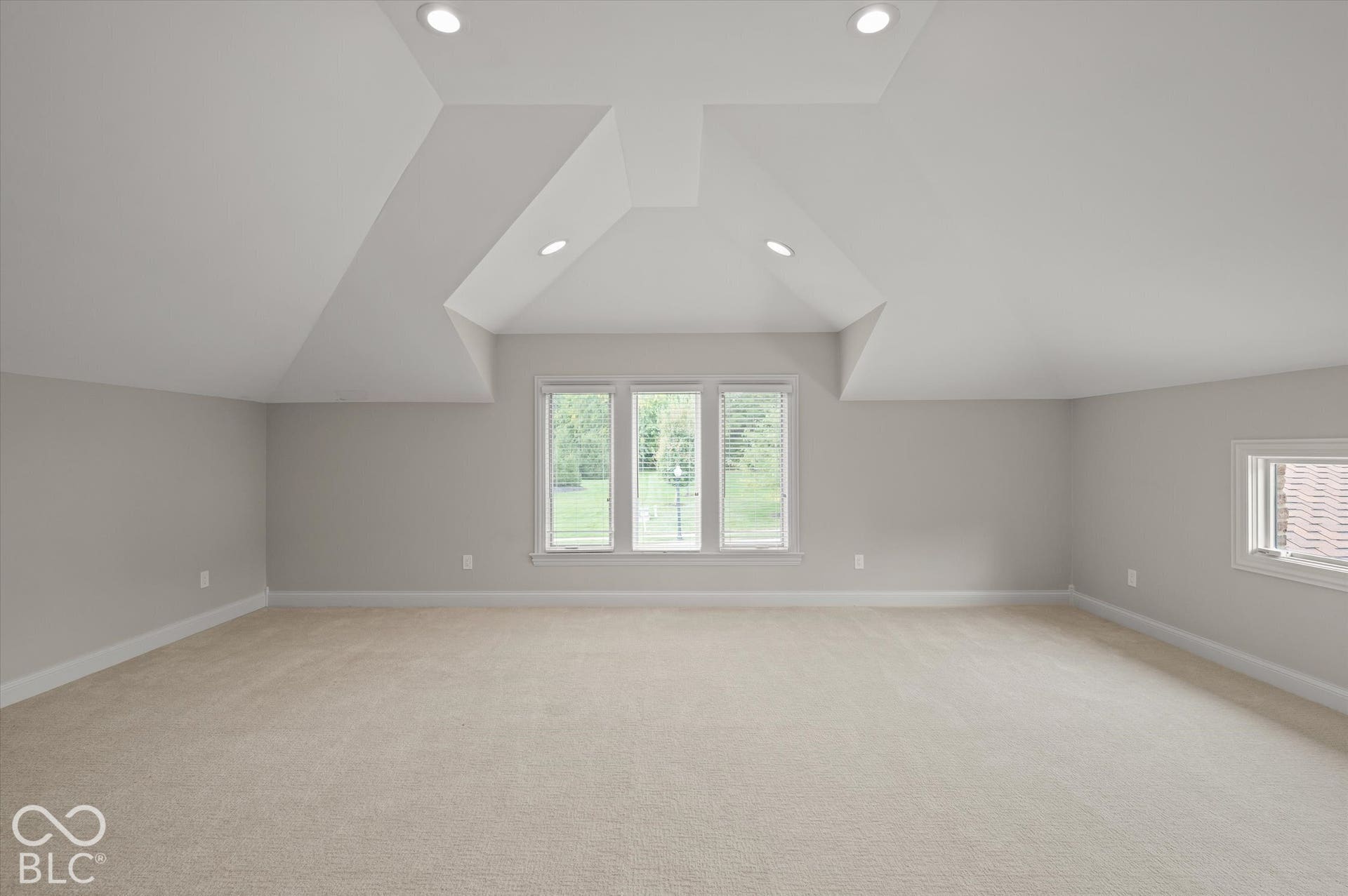 Recessed lighting illuminates the vaulted ceiling and neutral wall tones