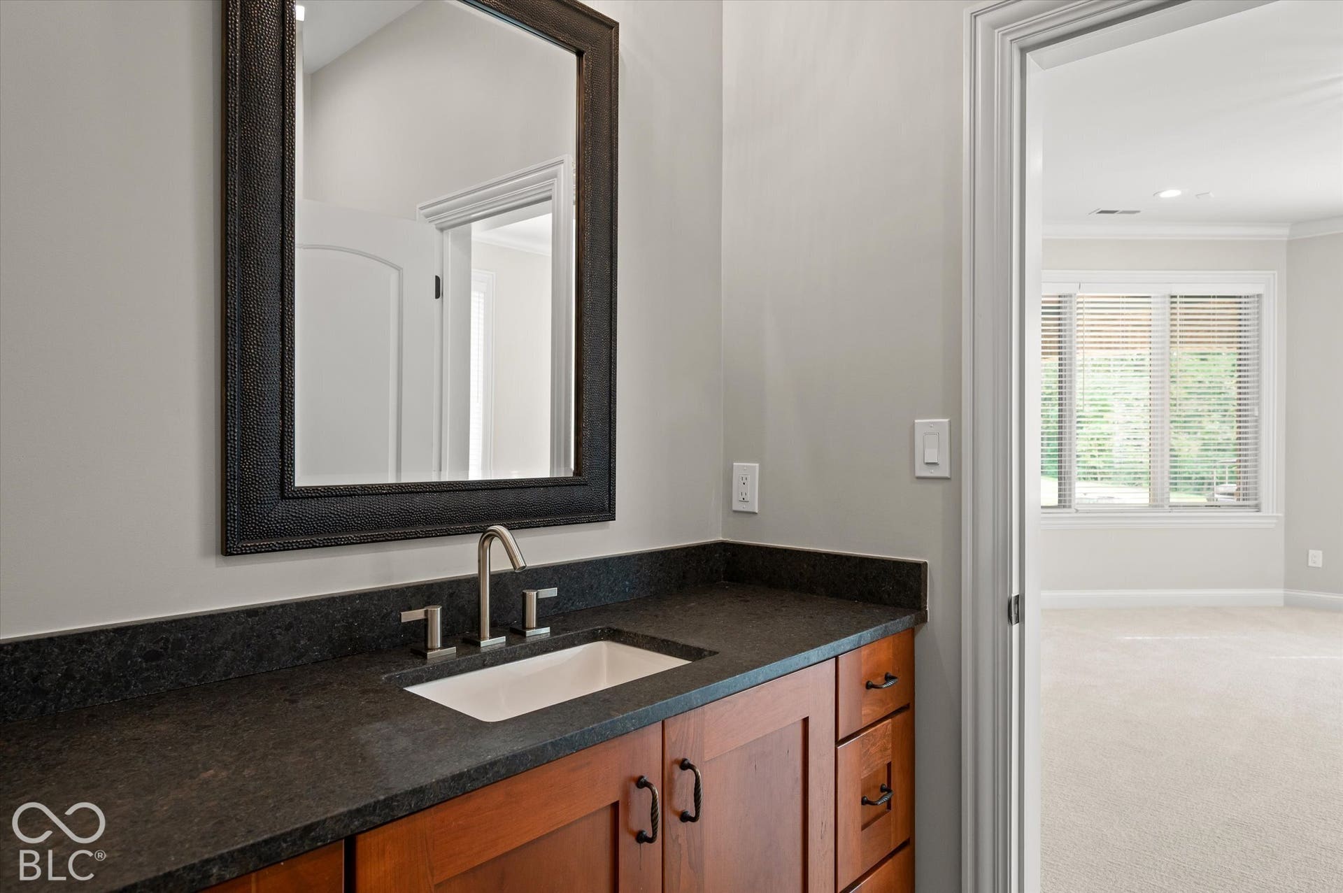 Vanity with a dark countertop, white rectangular sink, and brushed nickel faucet