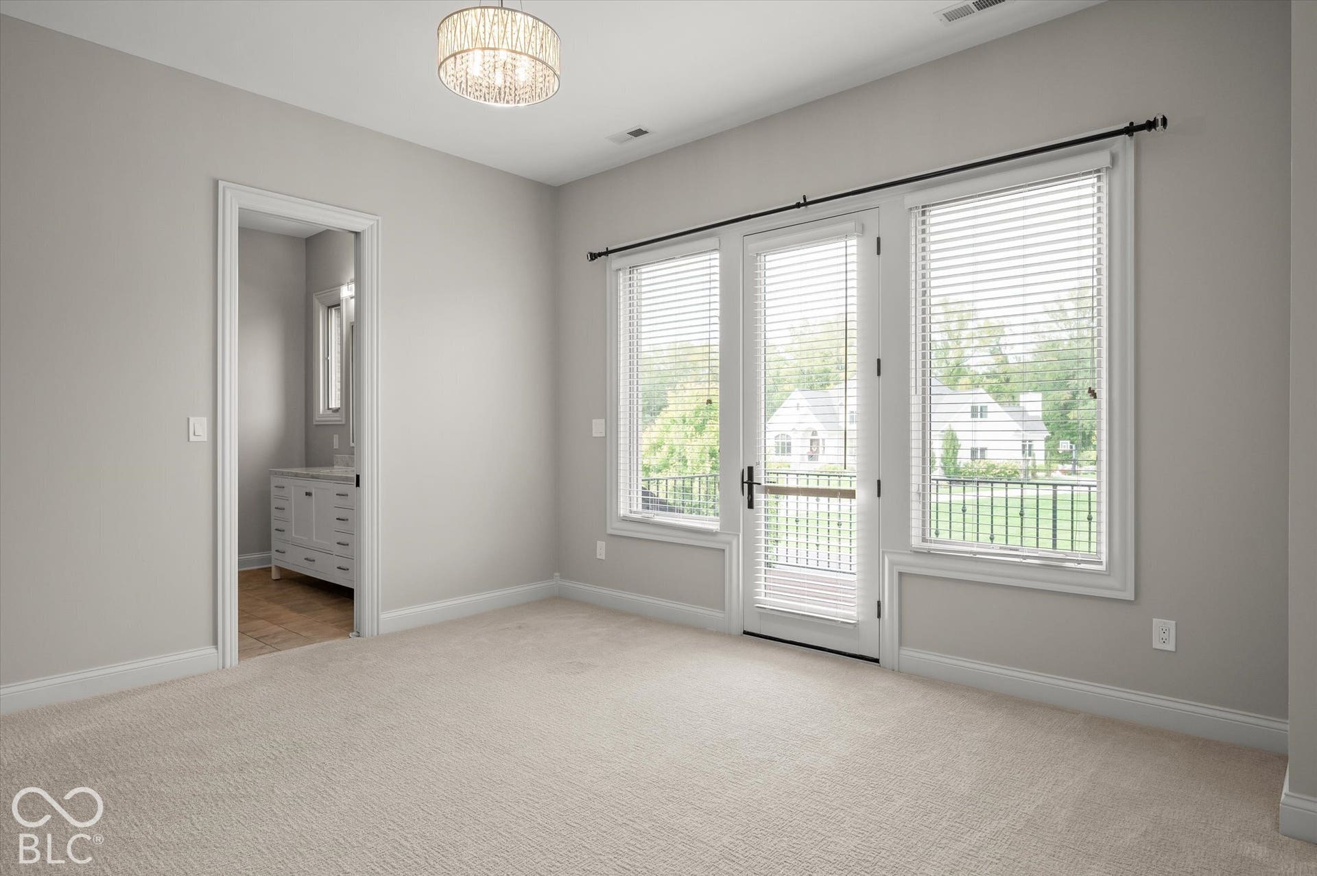 Carpeted flooring, chandelier lighting, French doors, balcony with iron railing, and a vanity with a rectangular sink