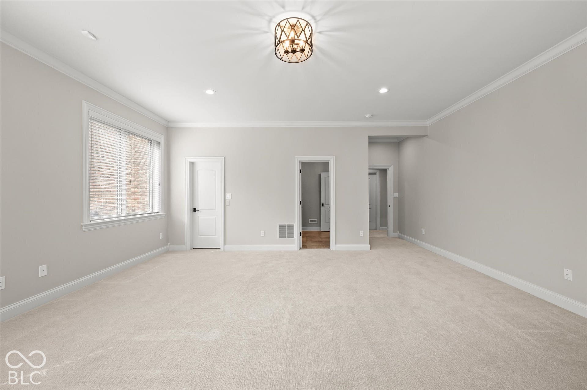 Recessed ceiling lighting, crown molding, a decorative ceiling fixture, and light-toned carpeting