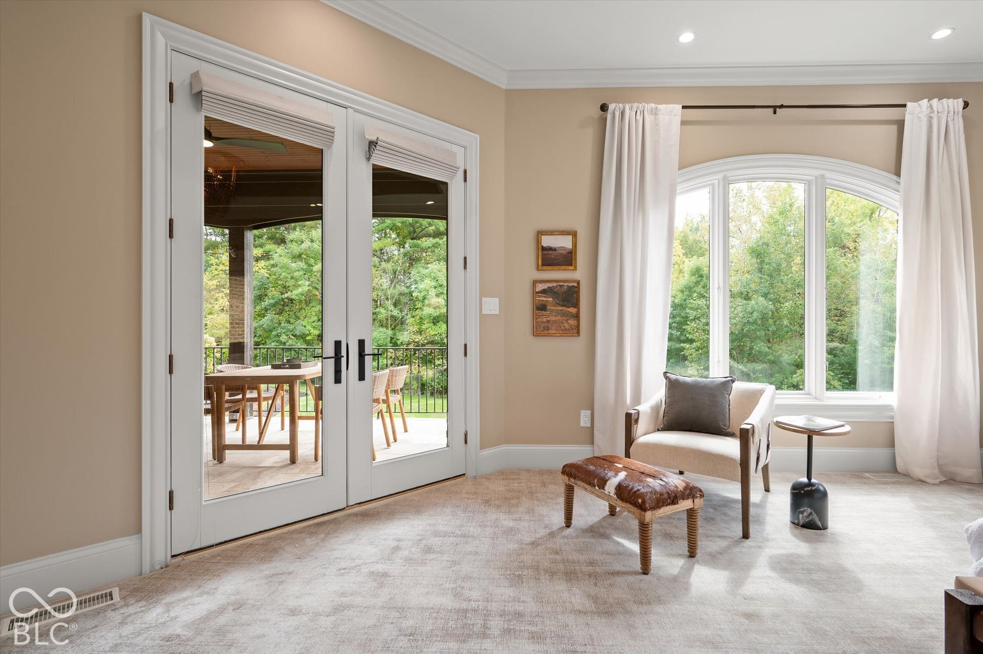 Double French doors leading to an outdoor space, arched window, recessed lighting, crown molding, and textured carpeting