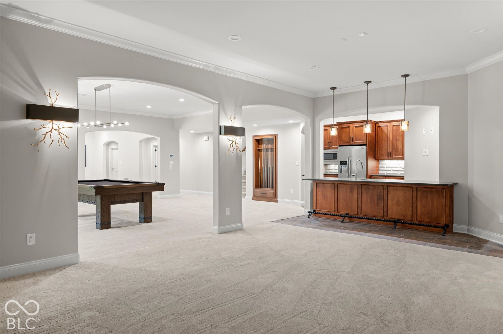 Open-concept recreation area featuring arched doorways, recessed lighting, and crown molding