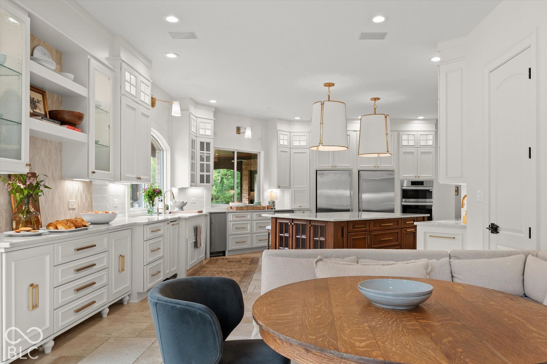 Expansive kitchen featuring white cabinetry, a wood-finish island, stainless steel appliances, and integrated lighting
