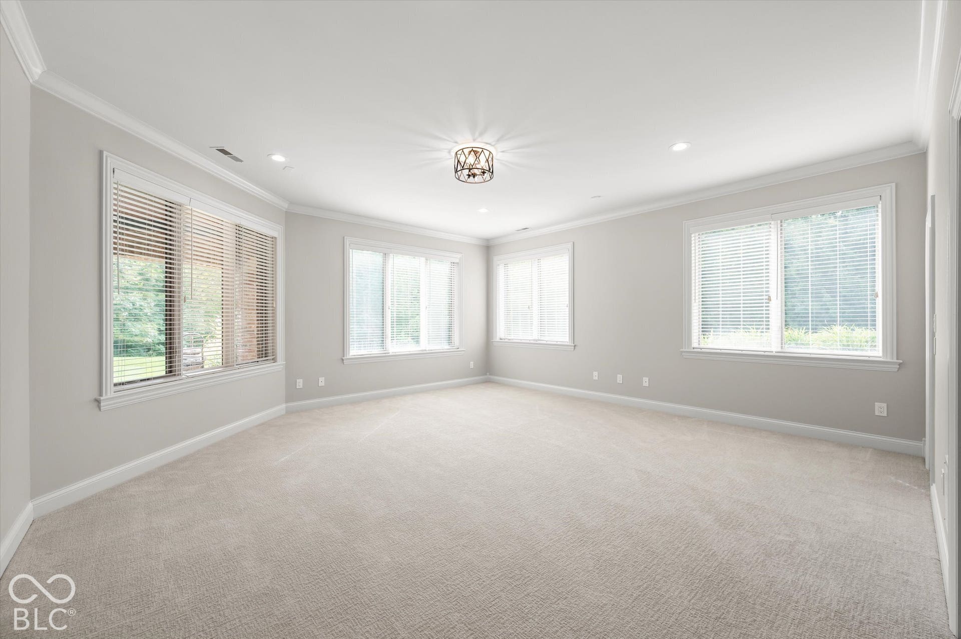 Neutral-toned carpeting, crown molding, multiple windows with blinds, recessed lighting, and a decorative ceiling fixture
