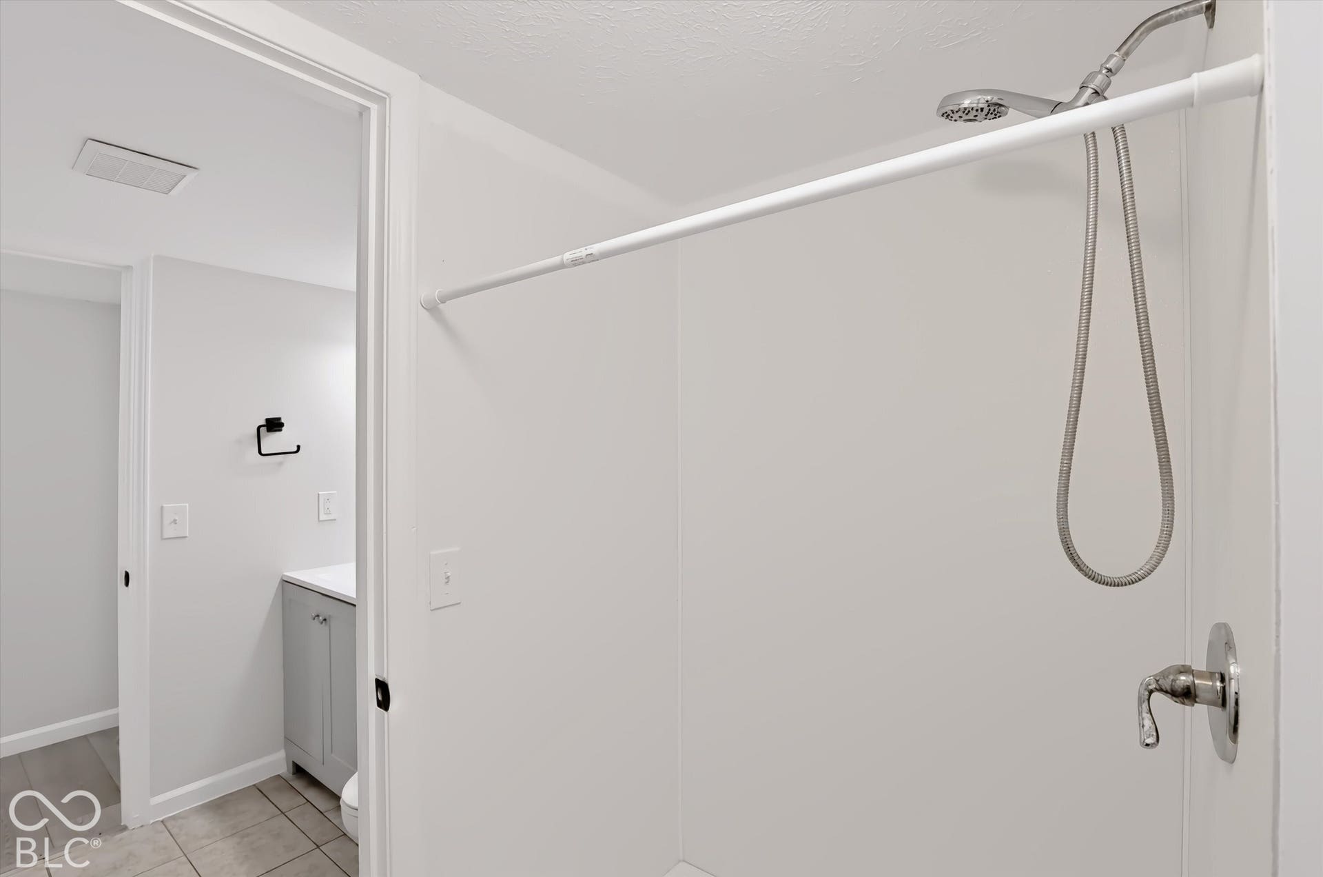 White shower surround with a handheld showerhead and brushed nickel fixtures