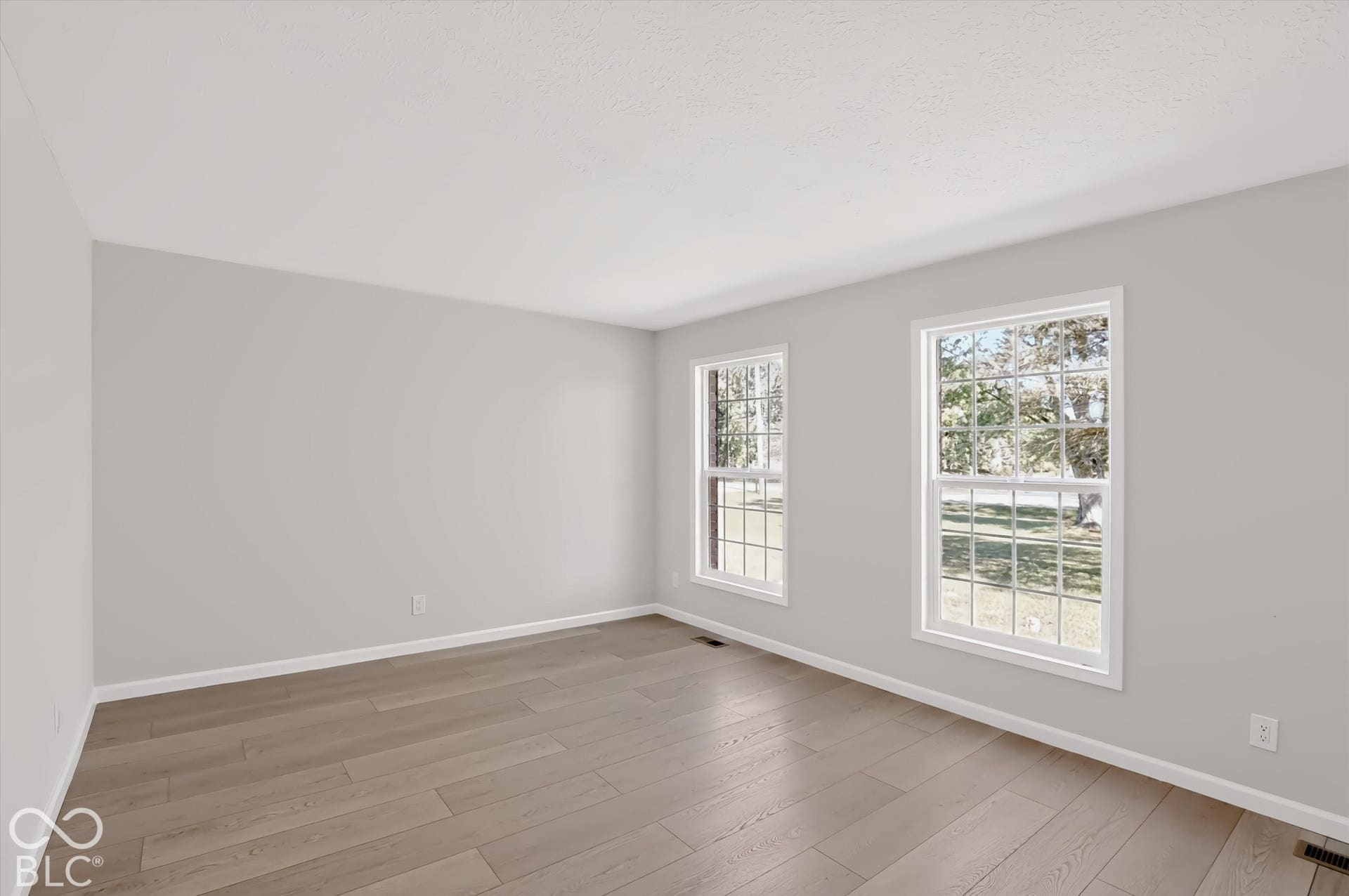 Neutral tone painted walls, wood-finish flooring, and multiple double-hung windows